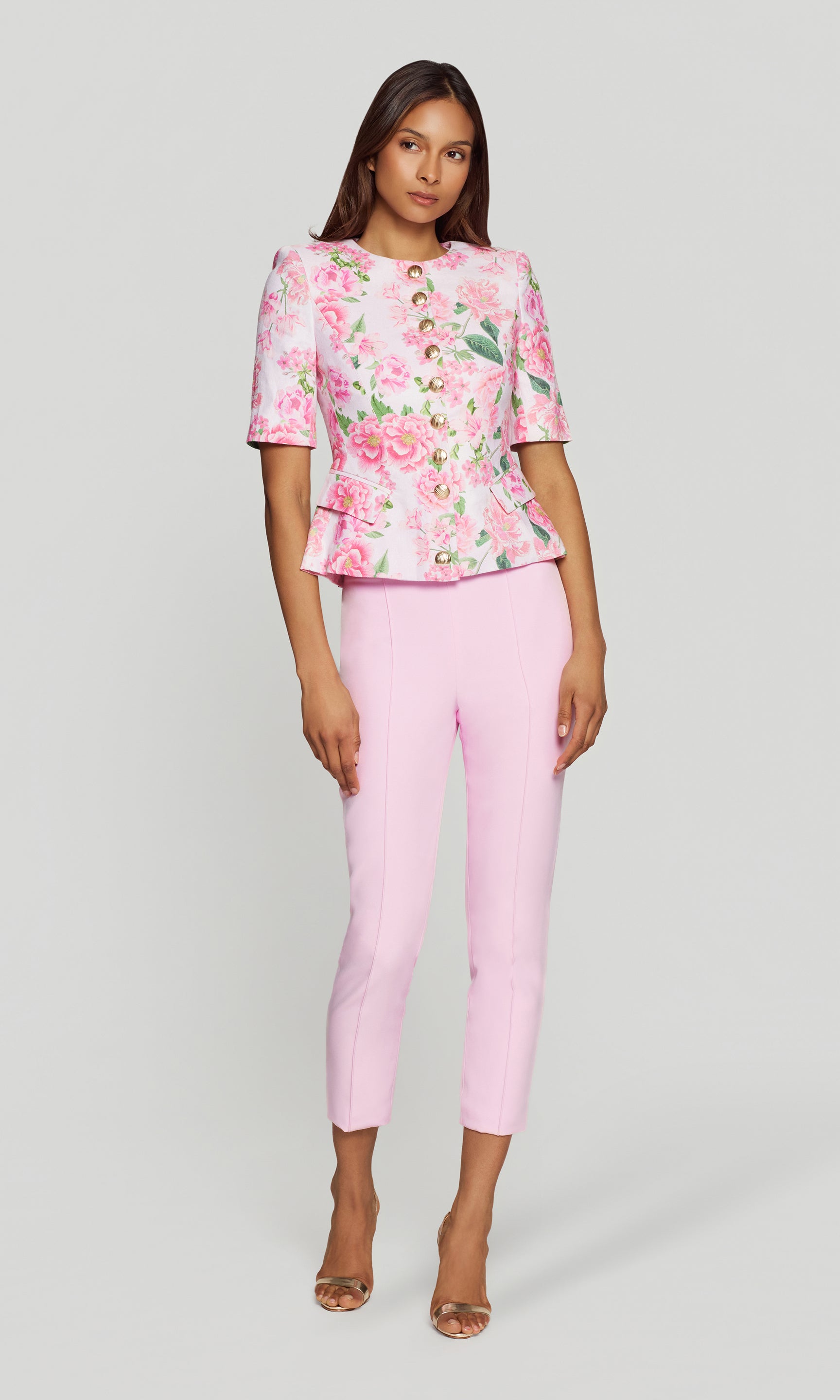 Woman wearing a pink floral jacket and pink pants on a white background
