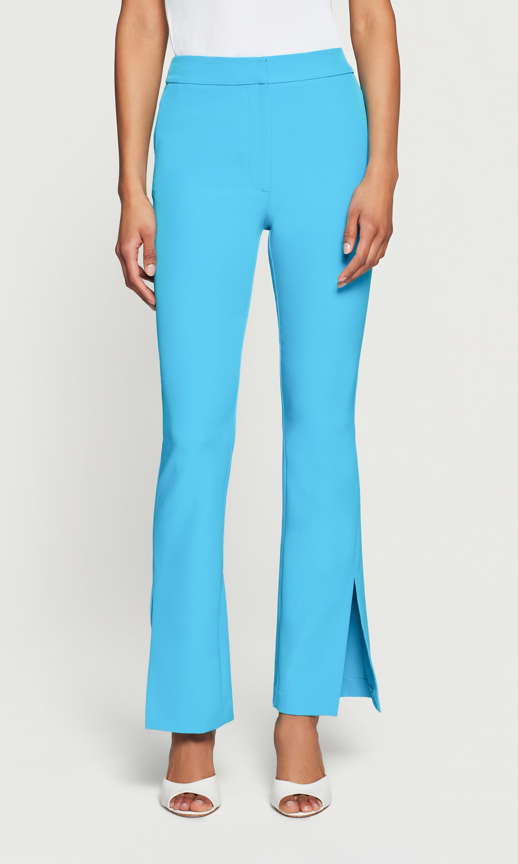 Blue pants with side leg slits worn by a person on a white background