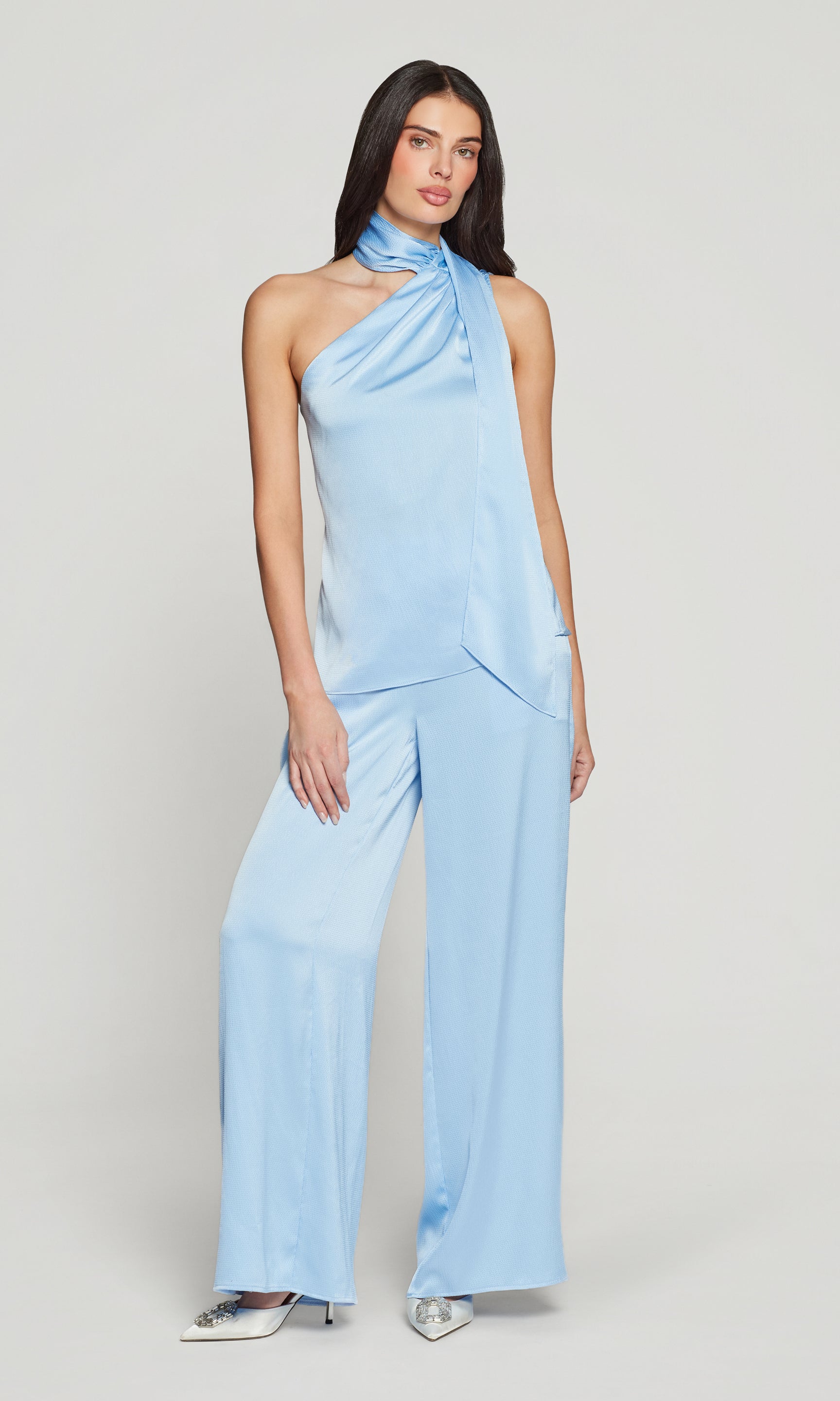 Woman wearing a light blue blouse and matching pant on a plain background