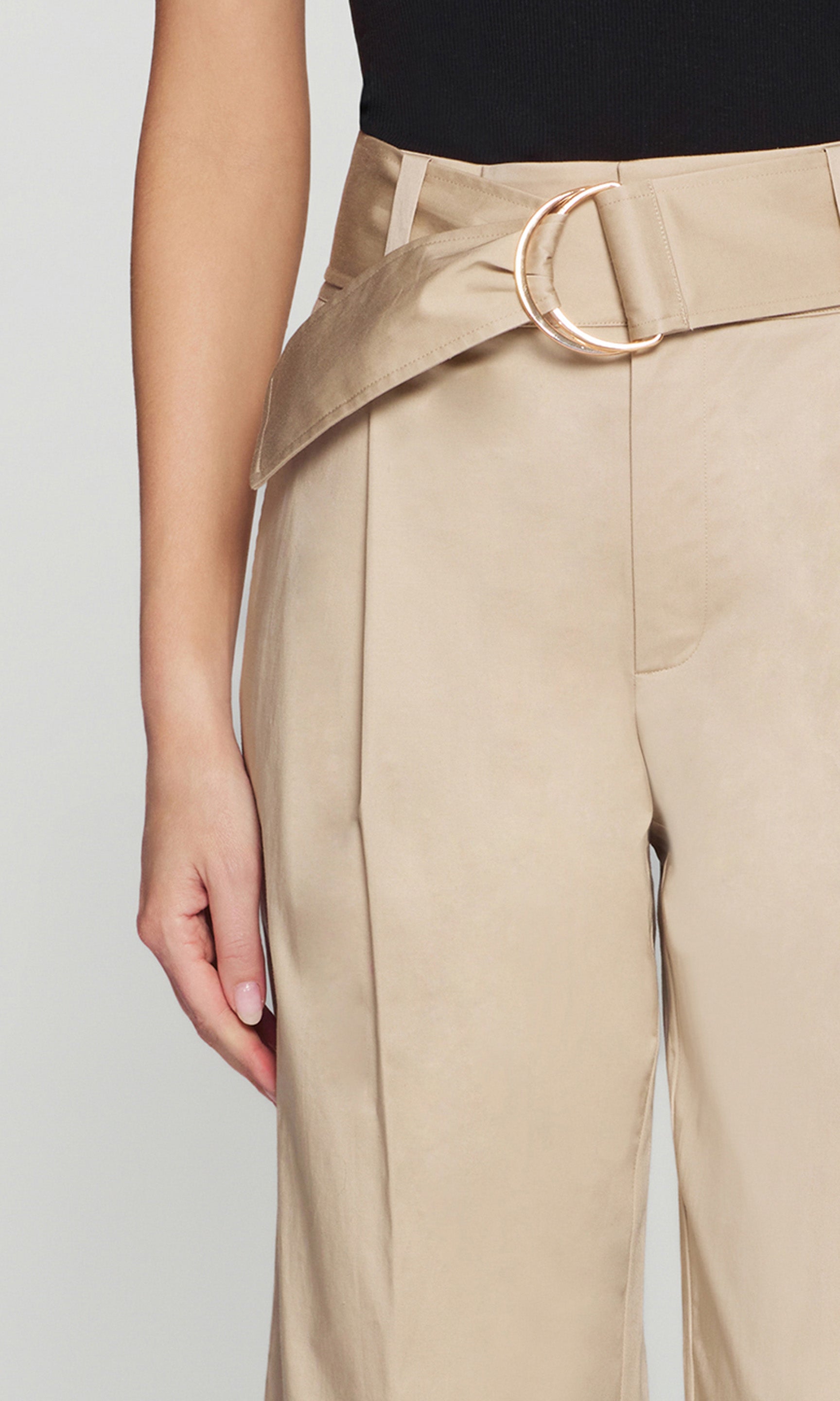 Model wears the Cassie Cotton Sateen Pants in light khaki in a close-up front view, focusing on the belt detail and waistband.