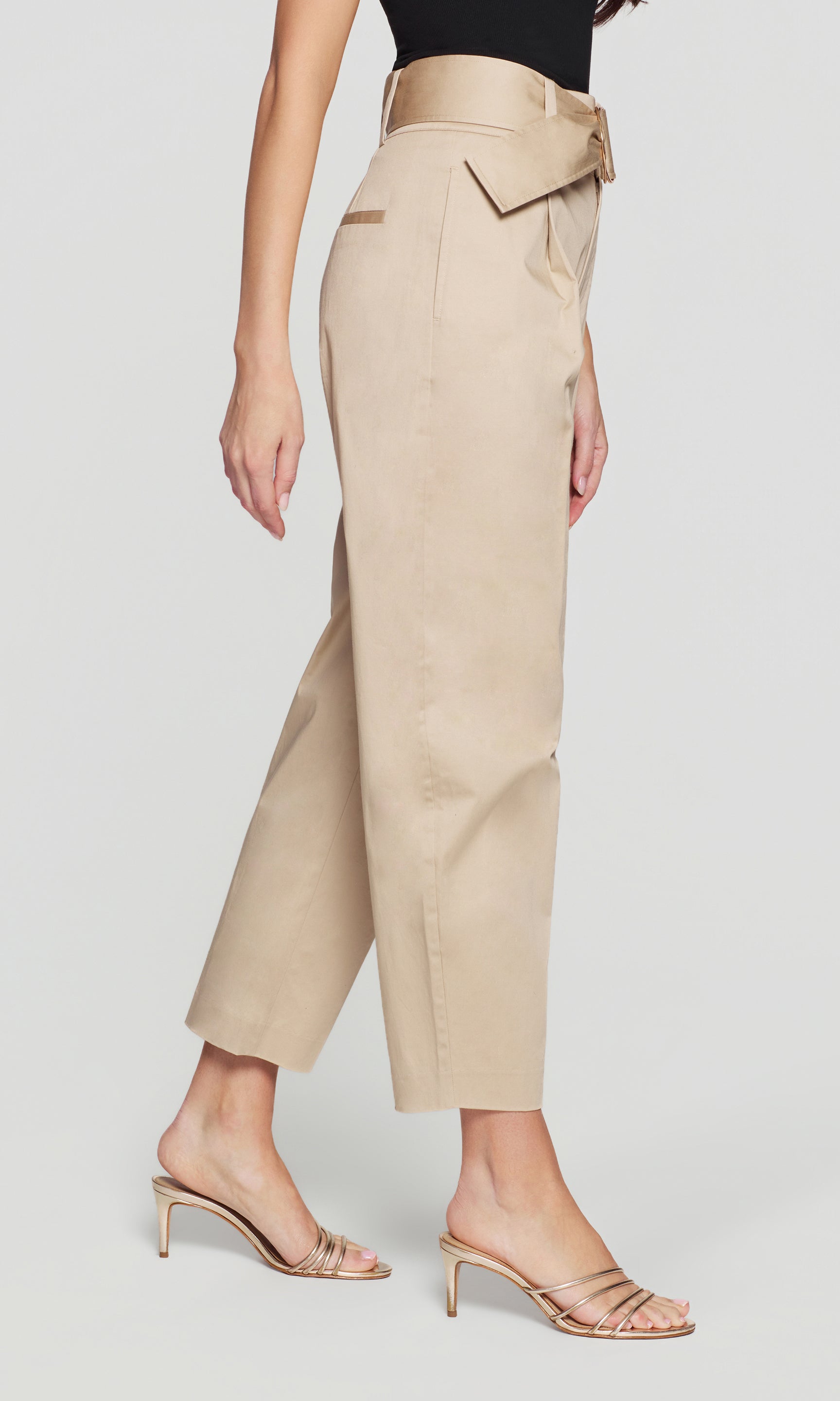 Model wears the Cassie Cotton Sateen Pants in light khaki in a side view (cropped), showing the pocket and leg shape.