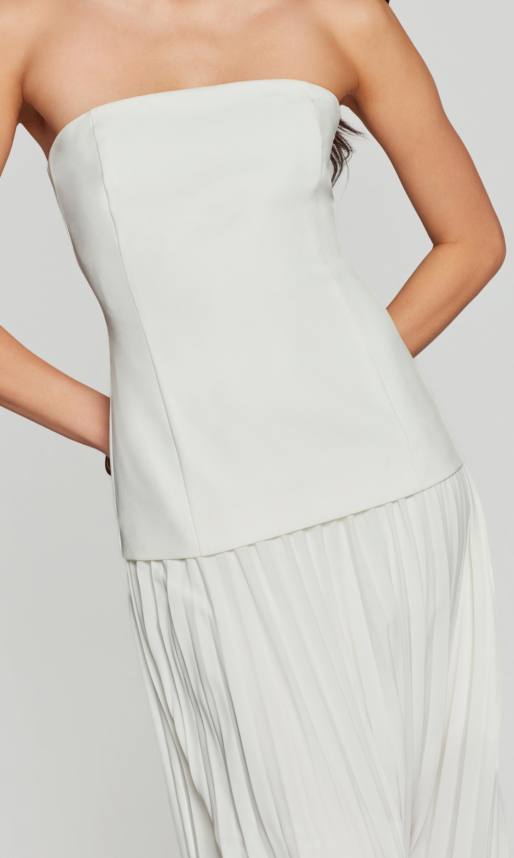 Light gray strapless dress with a pleated skirt on a plain background