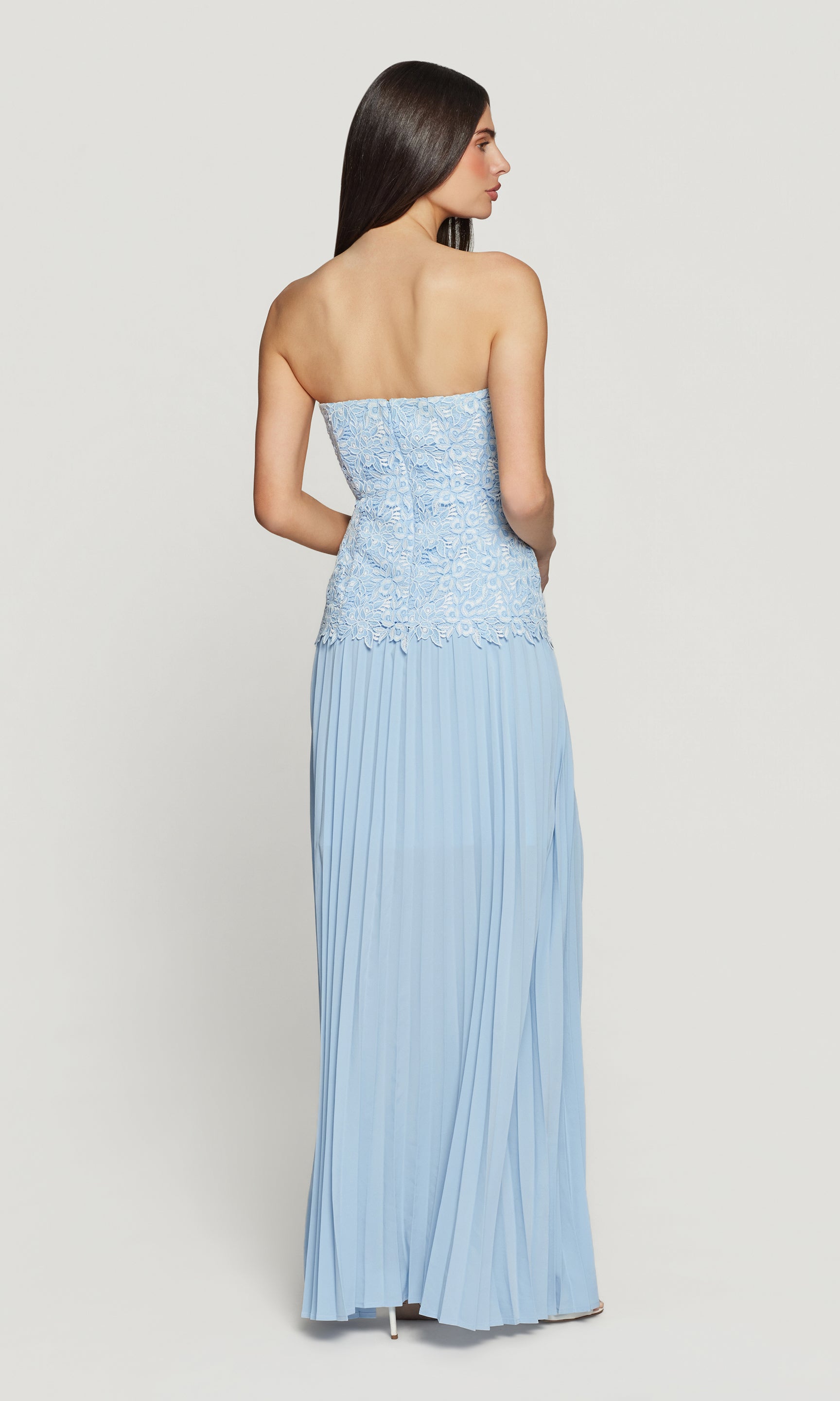 Back view of woman wearing a light blue strapless dress on a white background