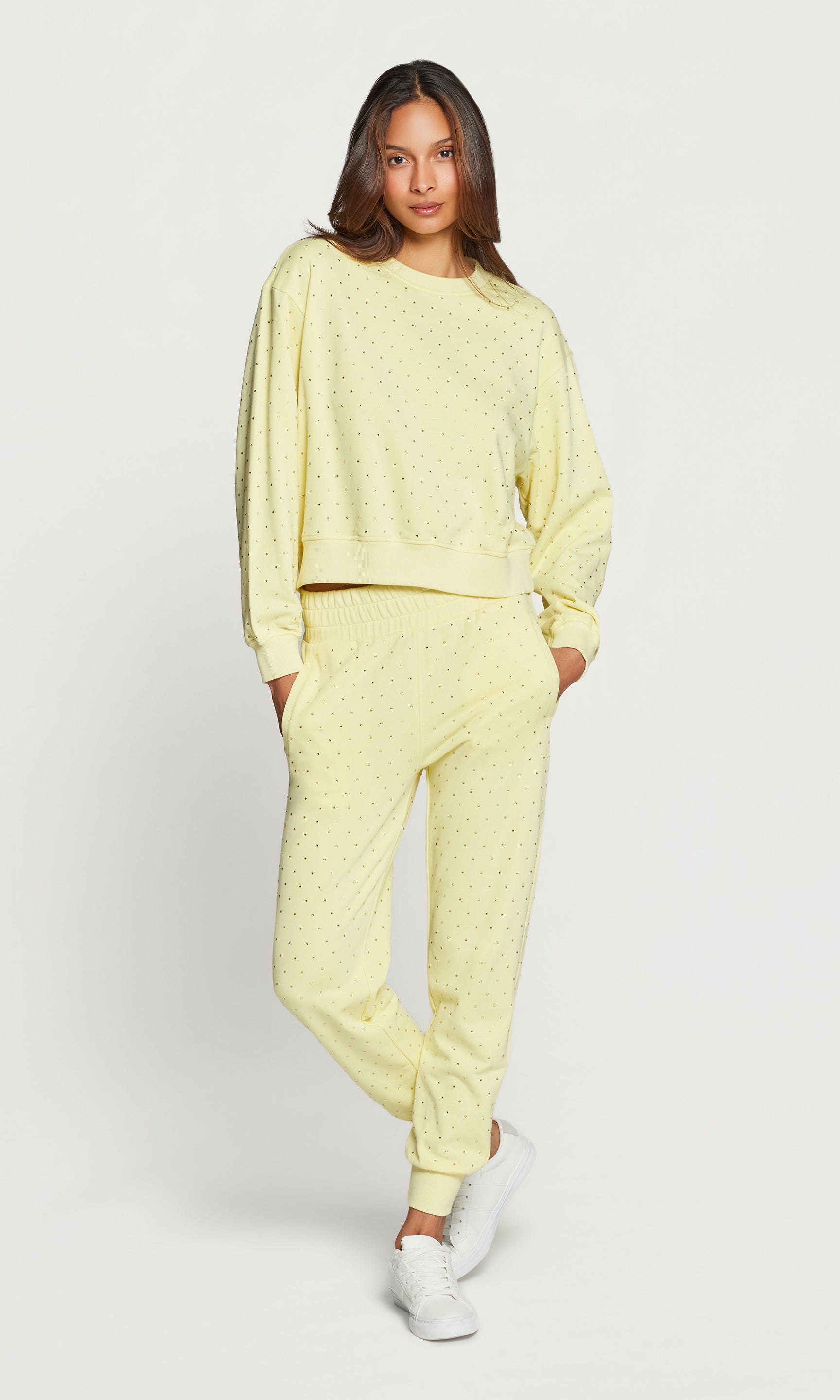 Woman wearing a light yellow lounge set with crystal embellishments on a white background