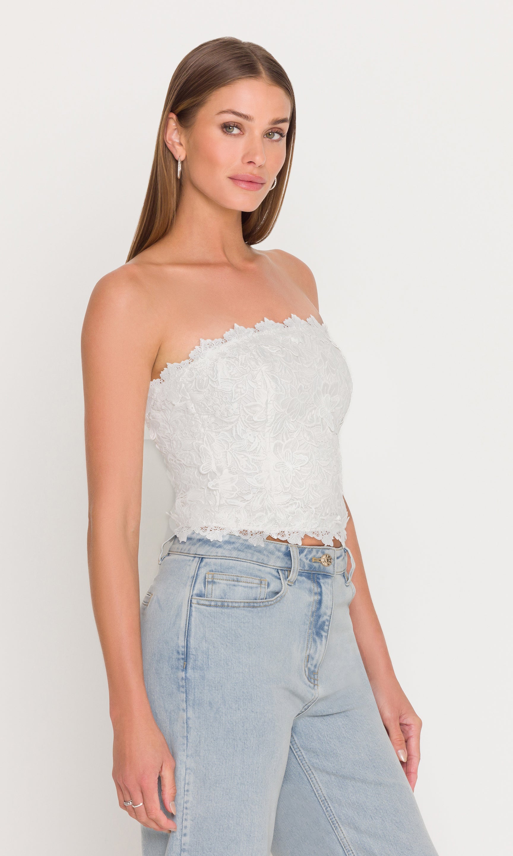 The model appears in a full body front view wearing the Daxi 3D Butterfly Lace Bustier in white with light wash jeans, highlighting a polished, feminine silhouette.