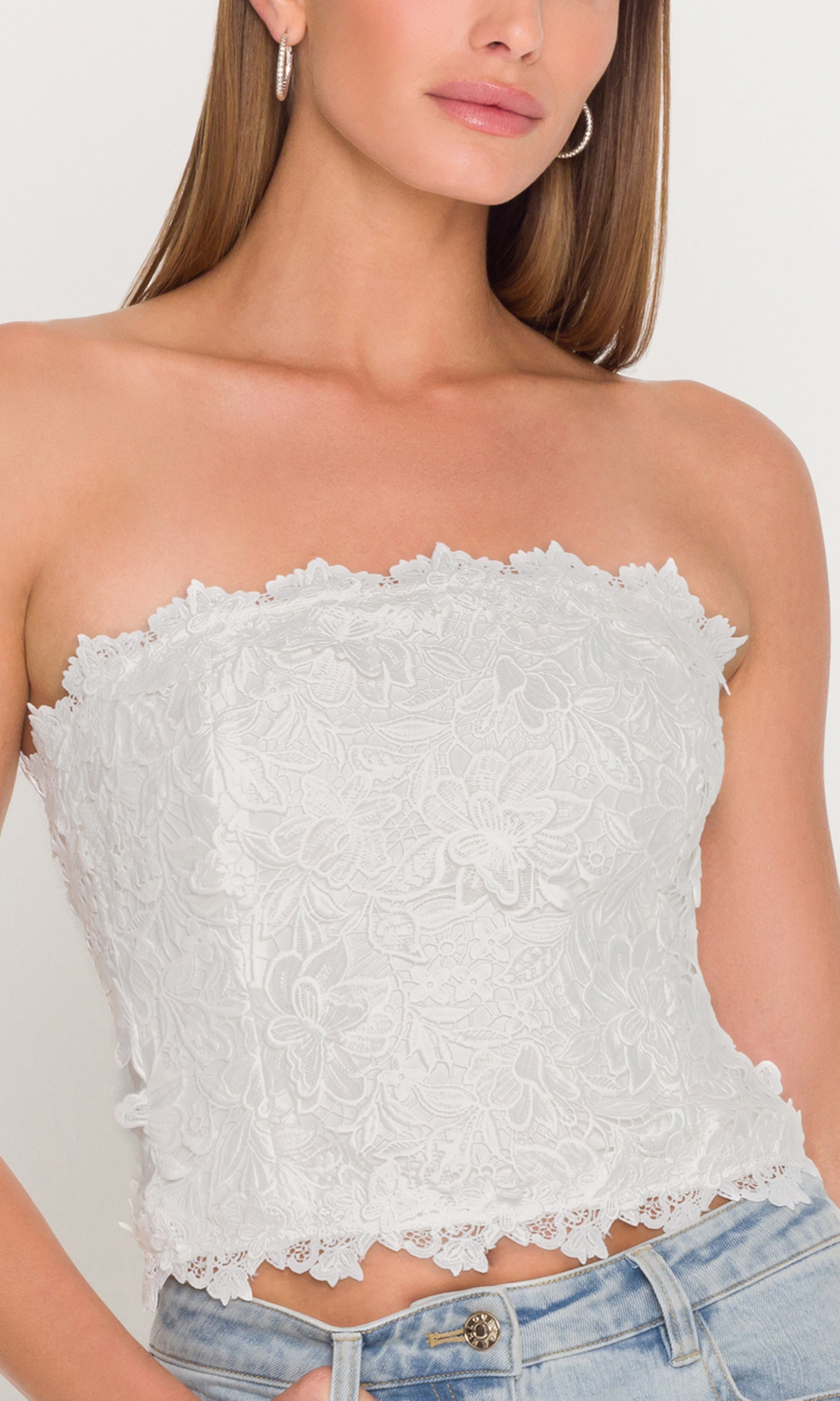 In a front view, the model styles the Daxi 3D Butterfly Lace Bustier in white with light wash denim, showcasing the fitted bustier shape and delicate lace hem.