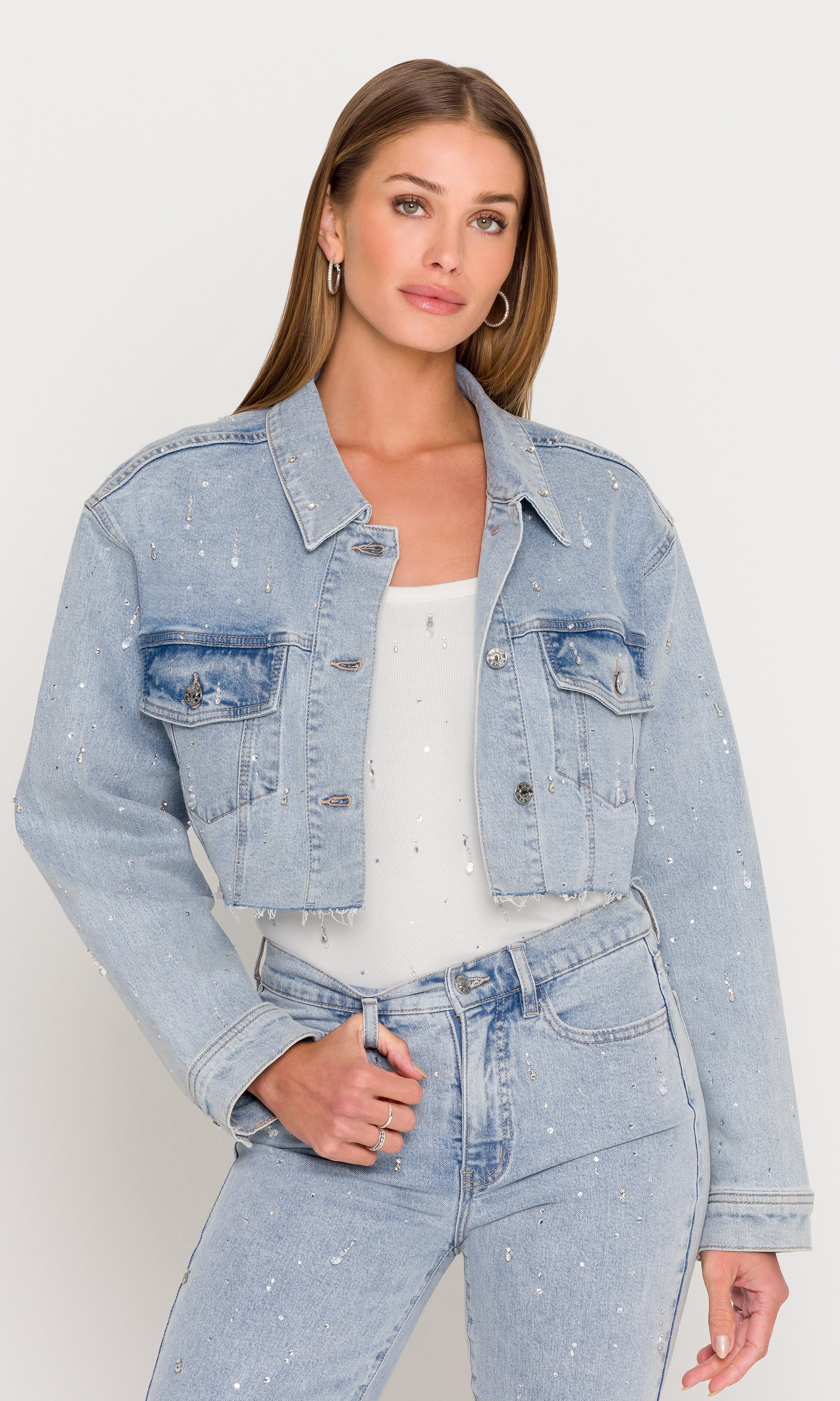 Woman wearing a light blue denim jacket and jeans on a white background