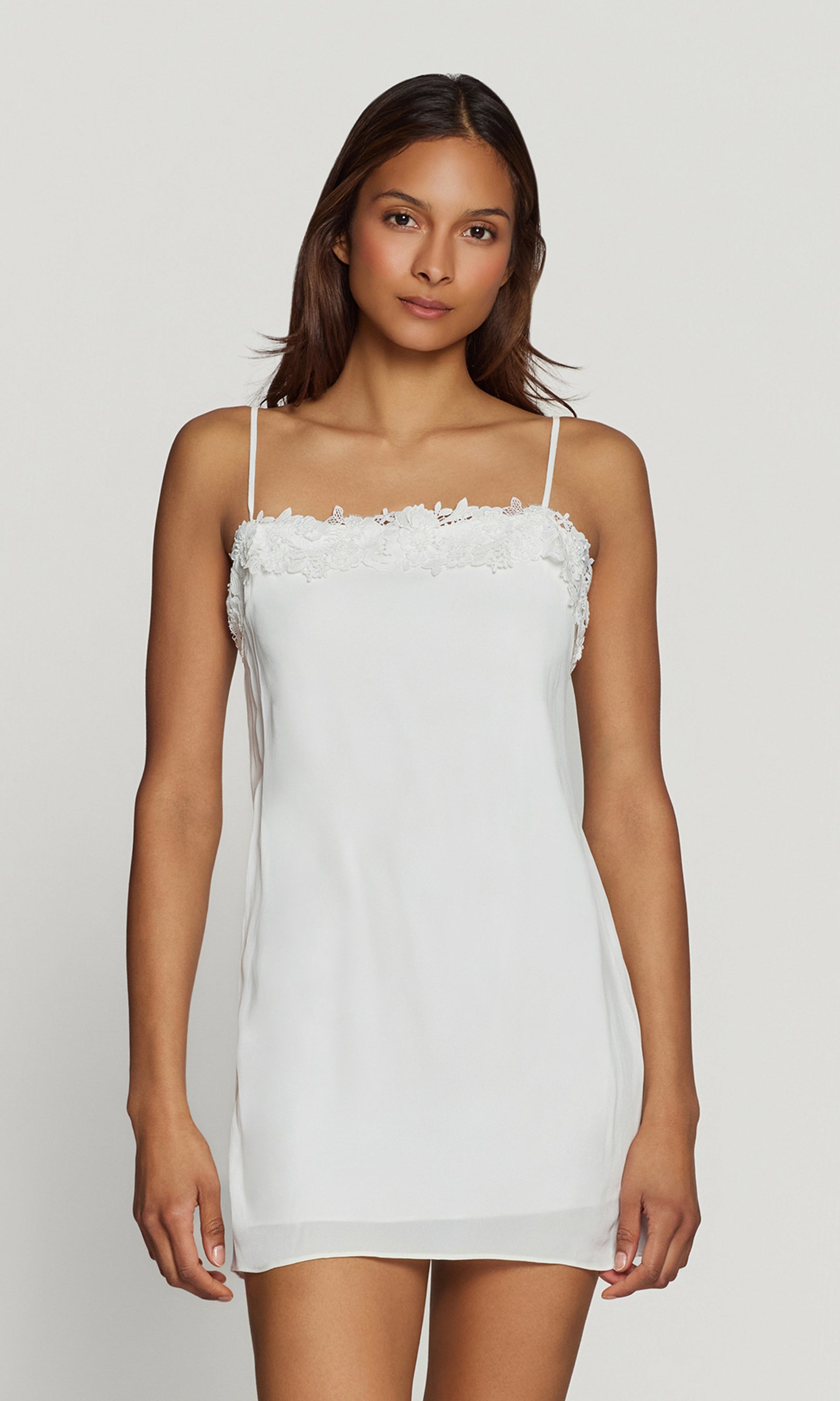 Woman wearing a white lace dress against a plain background