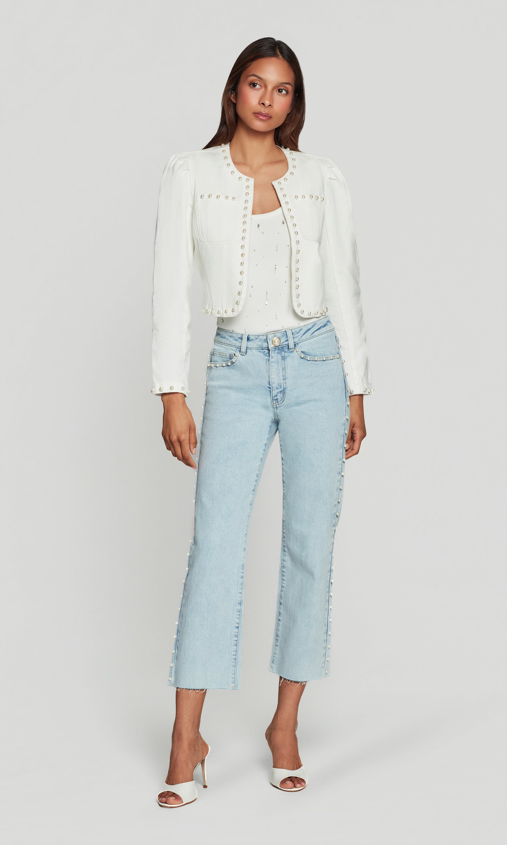 Woman wearing a white jacket and light blue jeans on a white background