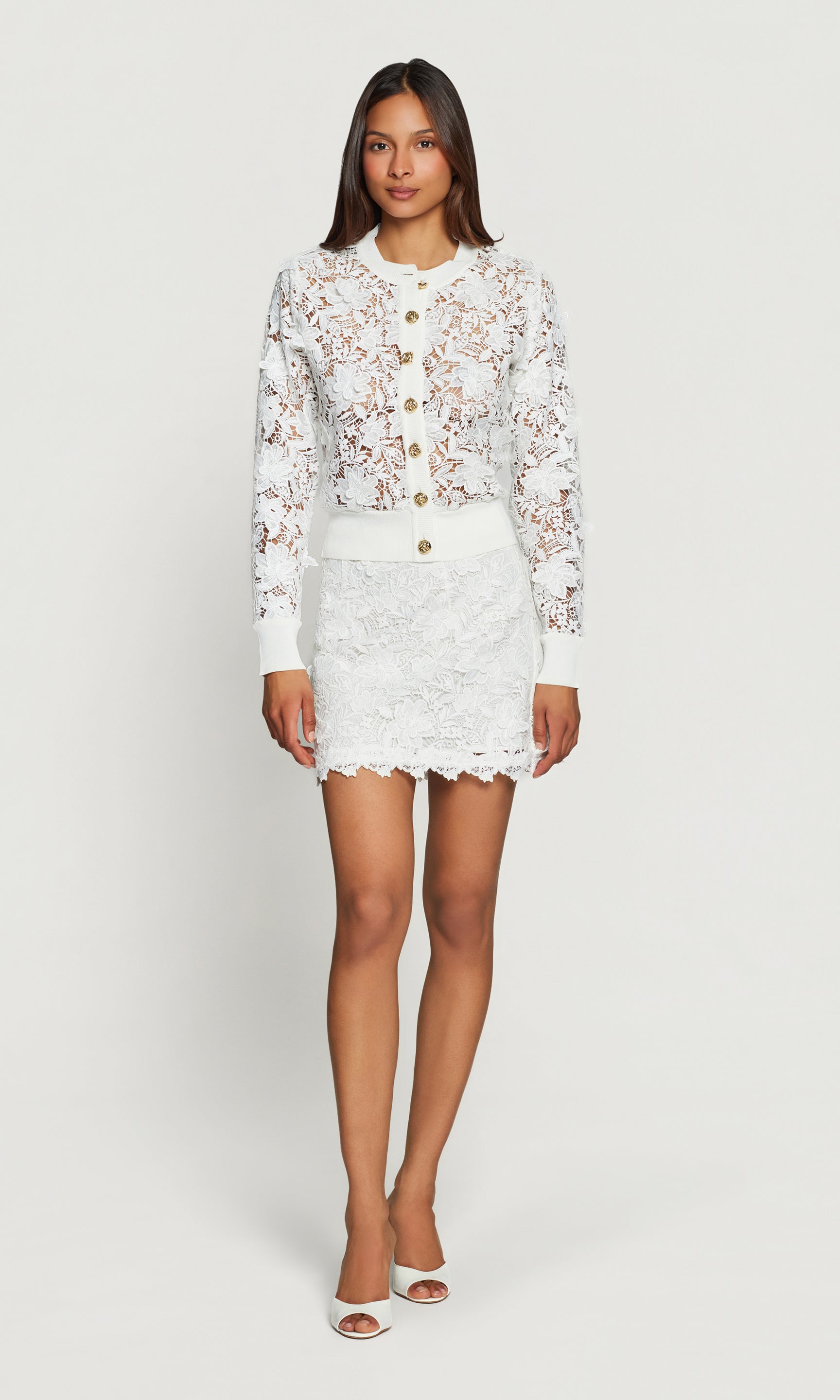 Woman wearing a white lace outfit on a plain background