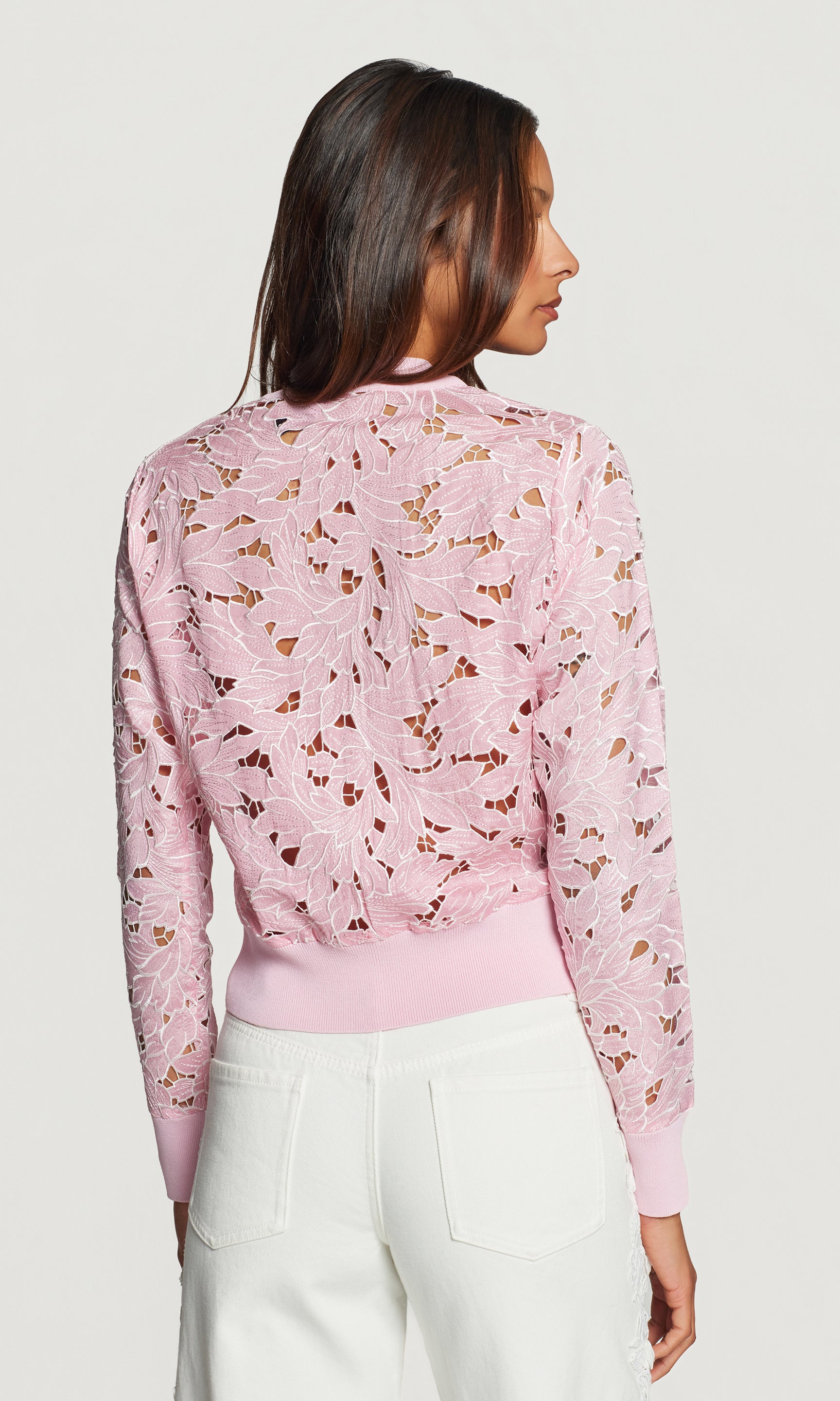Back view of woman wearing a pink floral-patterned sweater against a white background