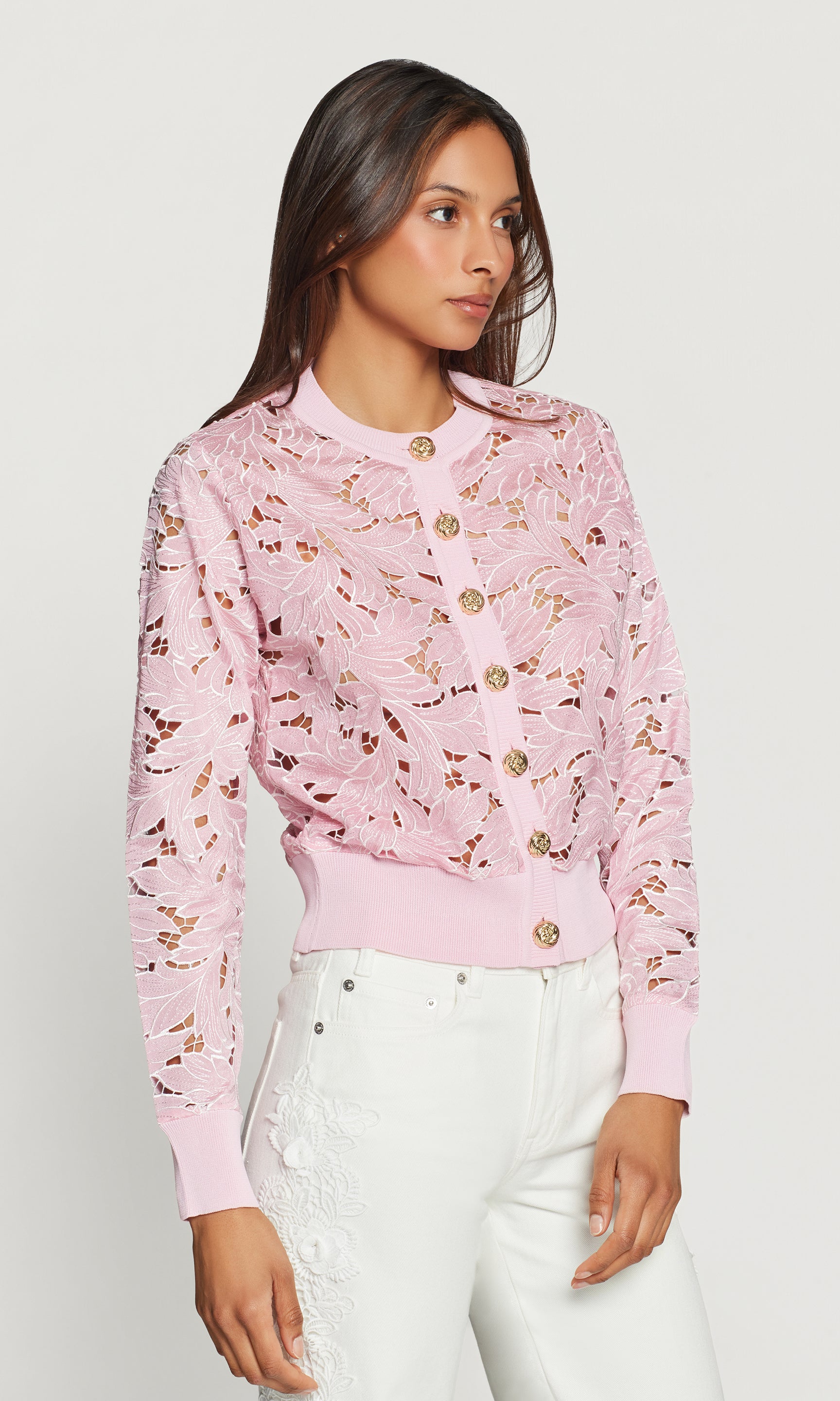 Side view of woman wearing a pink floral cardigan against a white background