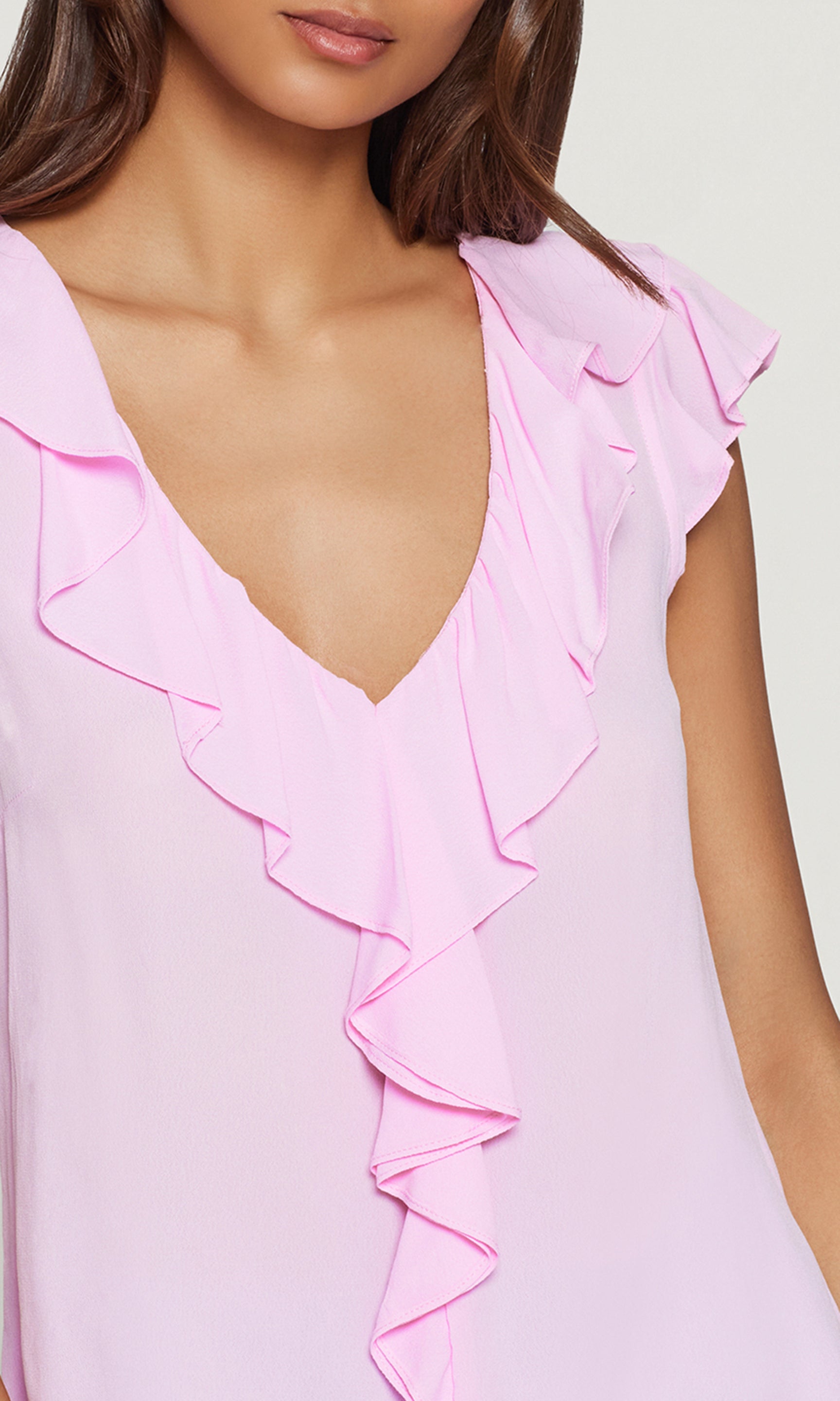 Close-up of a pink ruffled blouse with a plain background
