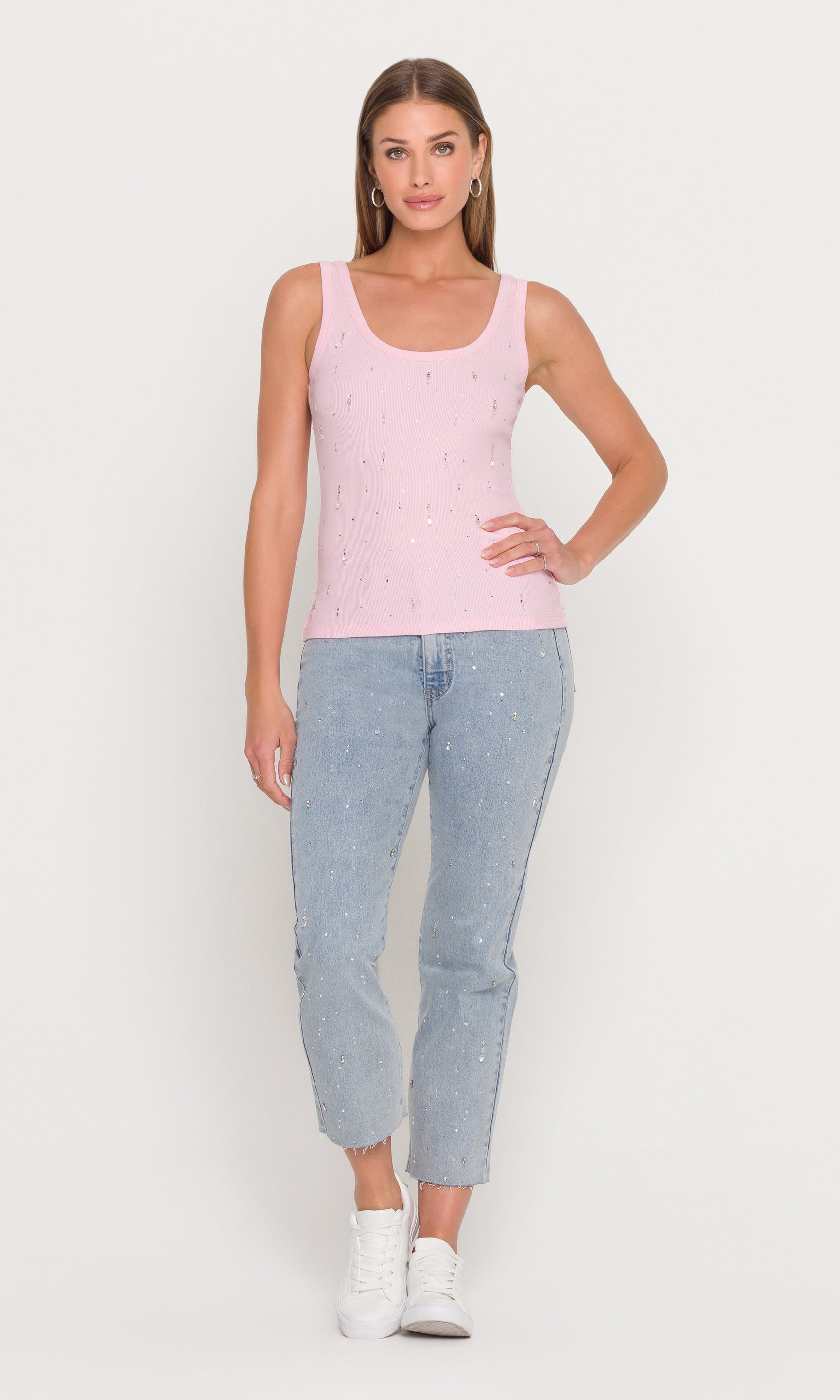 The model appears in a full body front view wearing the Evita Embellished Top in pink with jeans, highlighting the fitted shape and sparkling details.