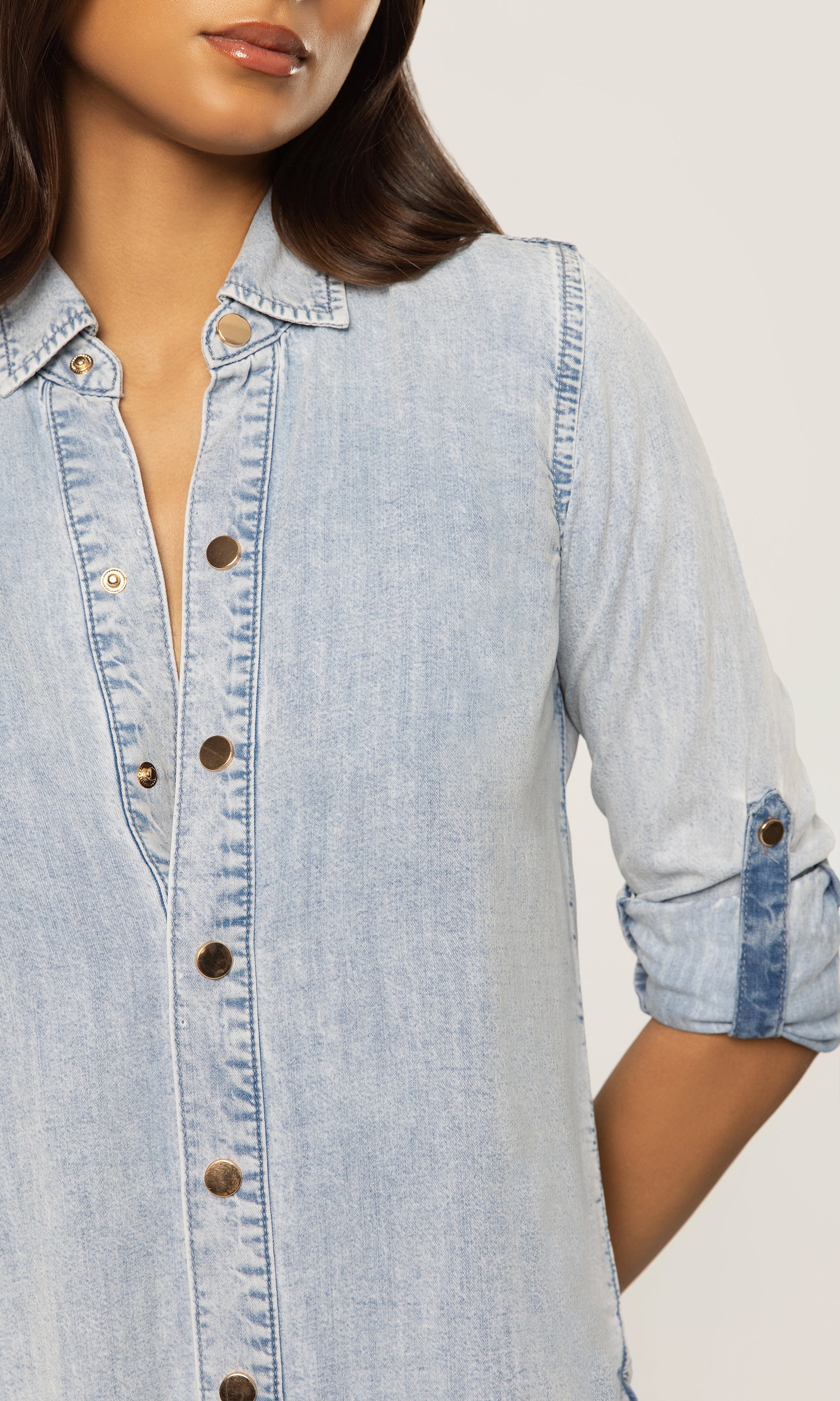Light blue denim shirt worn by a person on a plain background