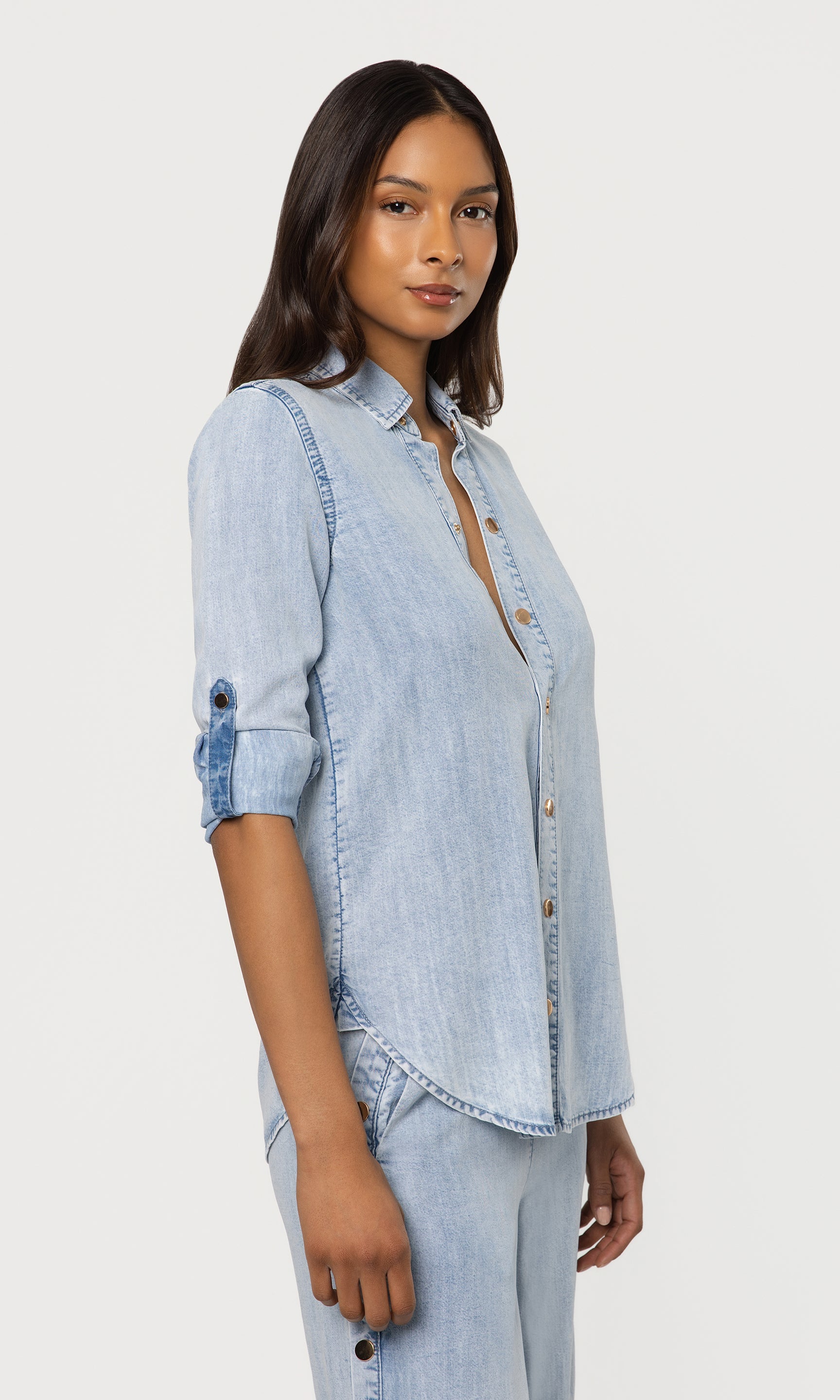 Woman wearing a light blue denim shirt and pants on a white background