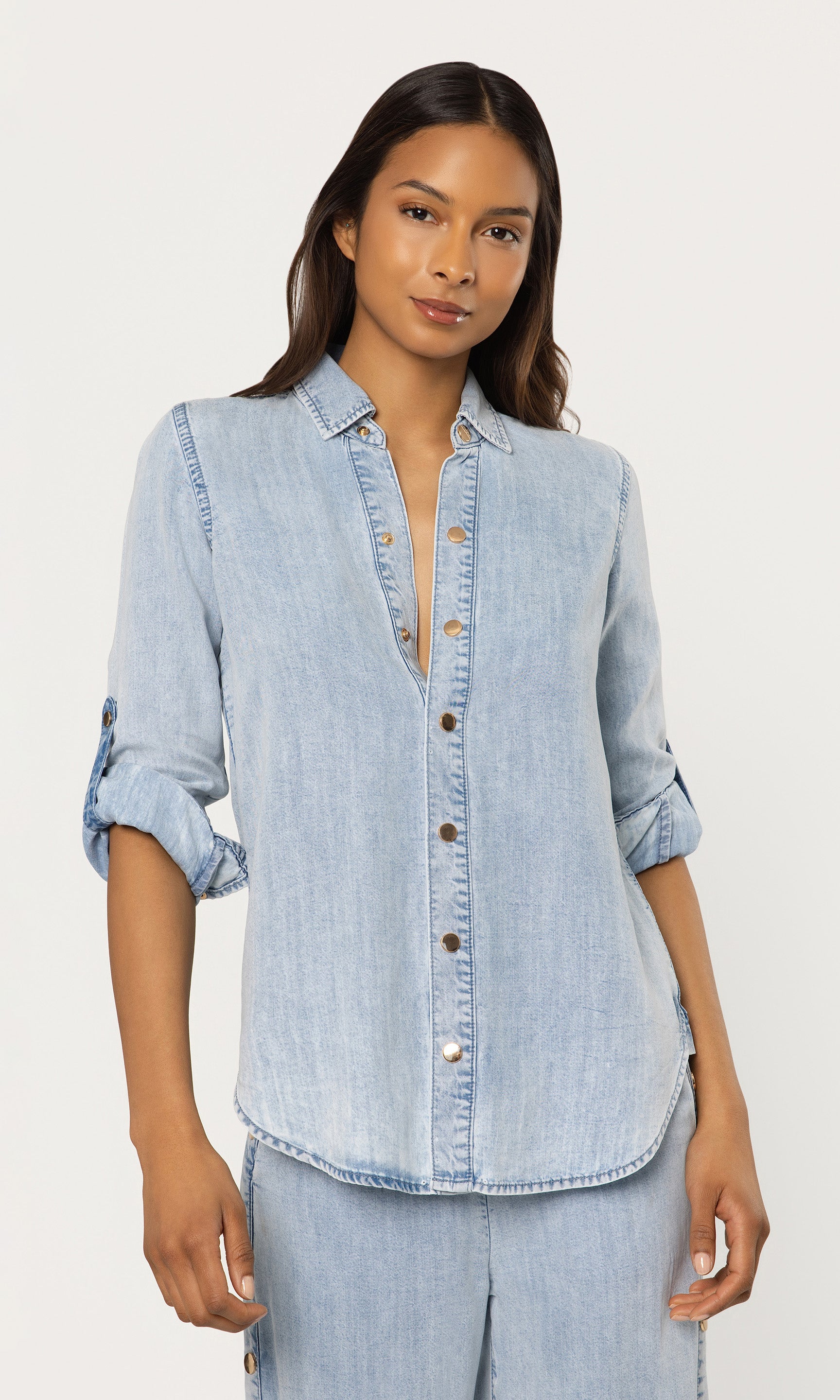 Woman wearing a light blue denim shirt on a white background