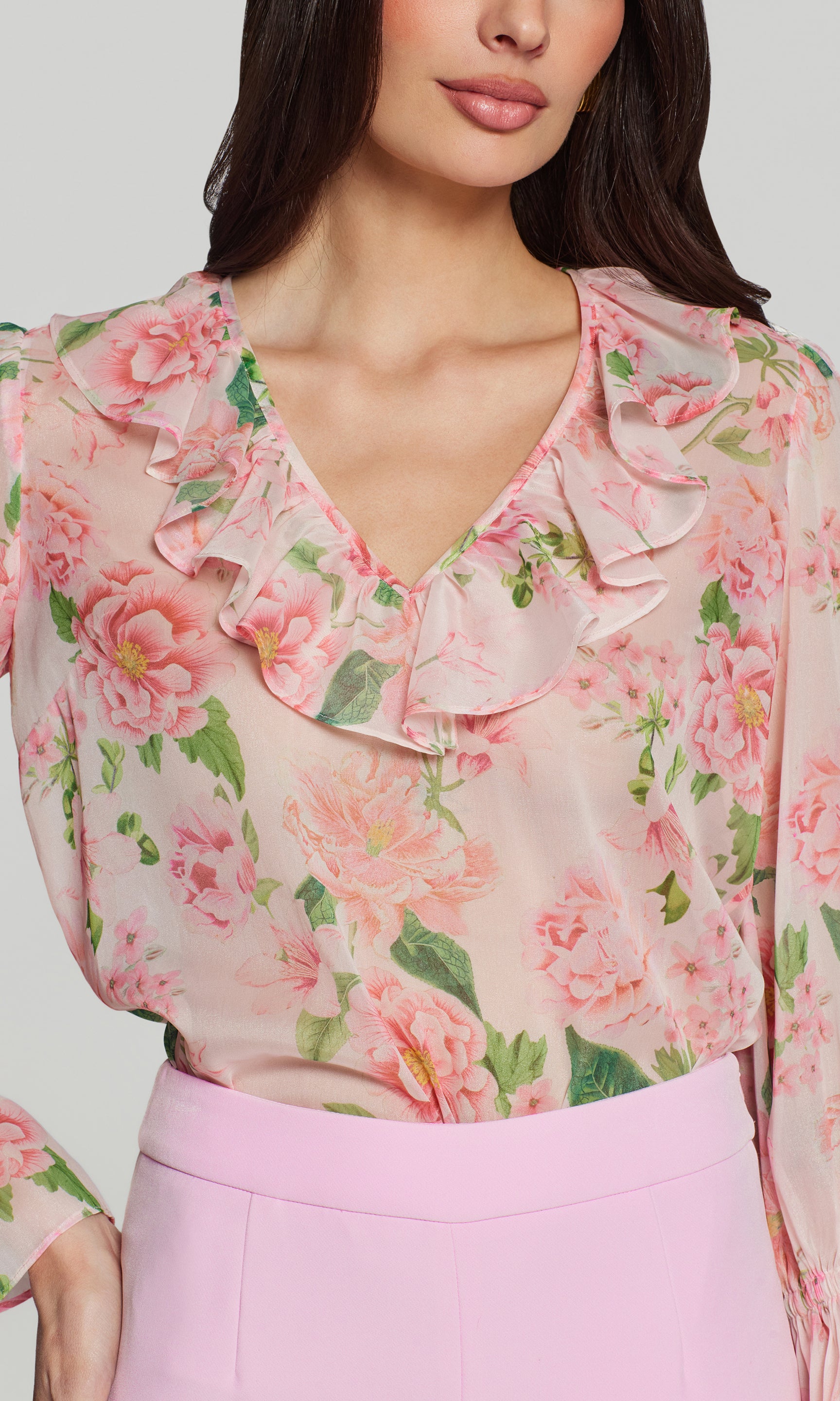 Close-up of woman wearing a floral blouse with ruffled details on a plain background
