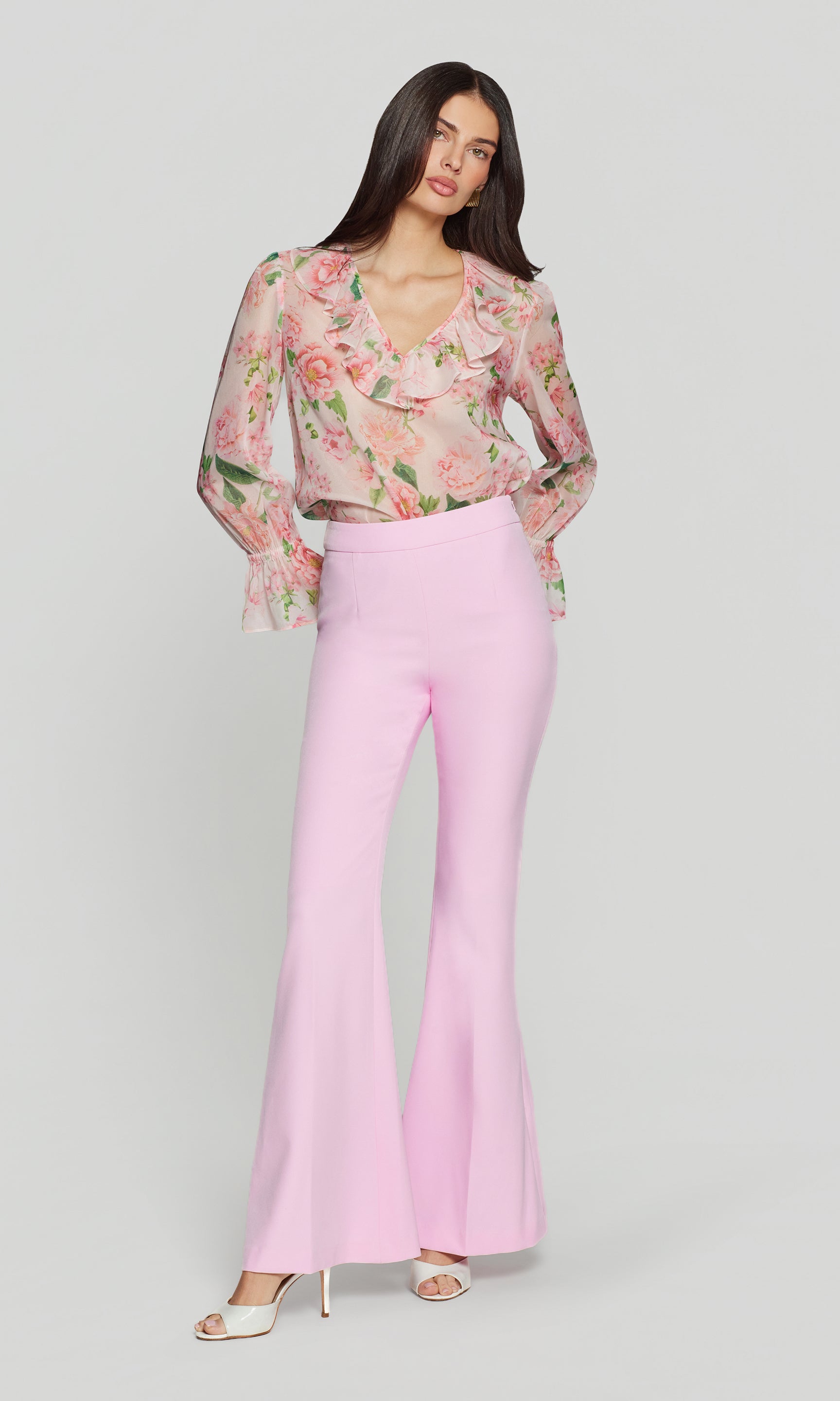 Woman wearing a floral blouse and pink pants on a white background
