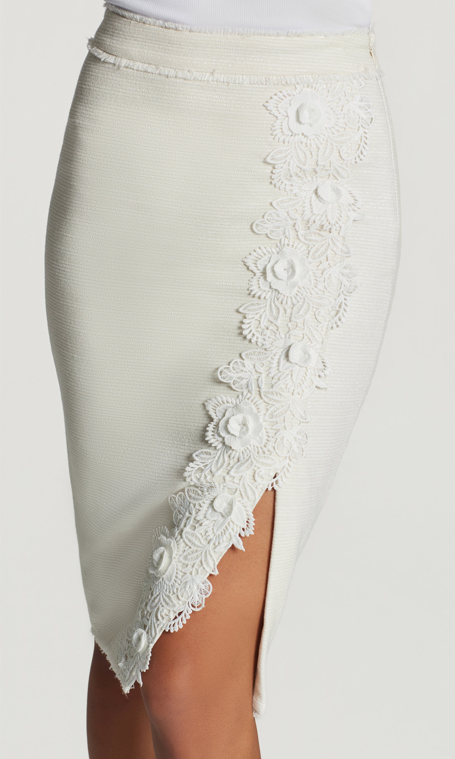 Close-up of white pencil skirt with lace detailing on a plain background