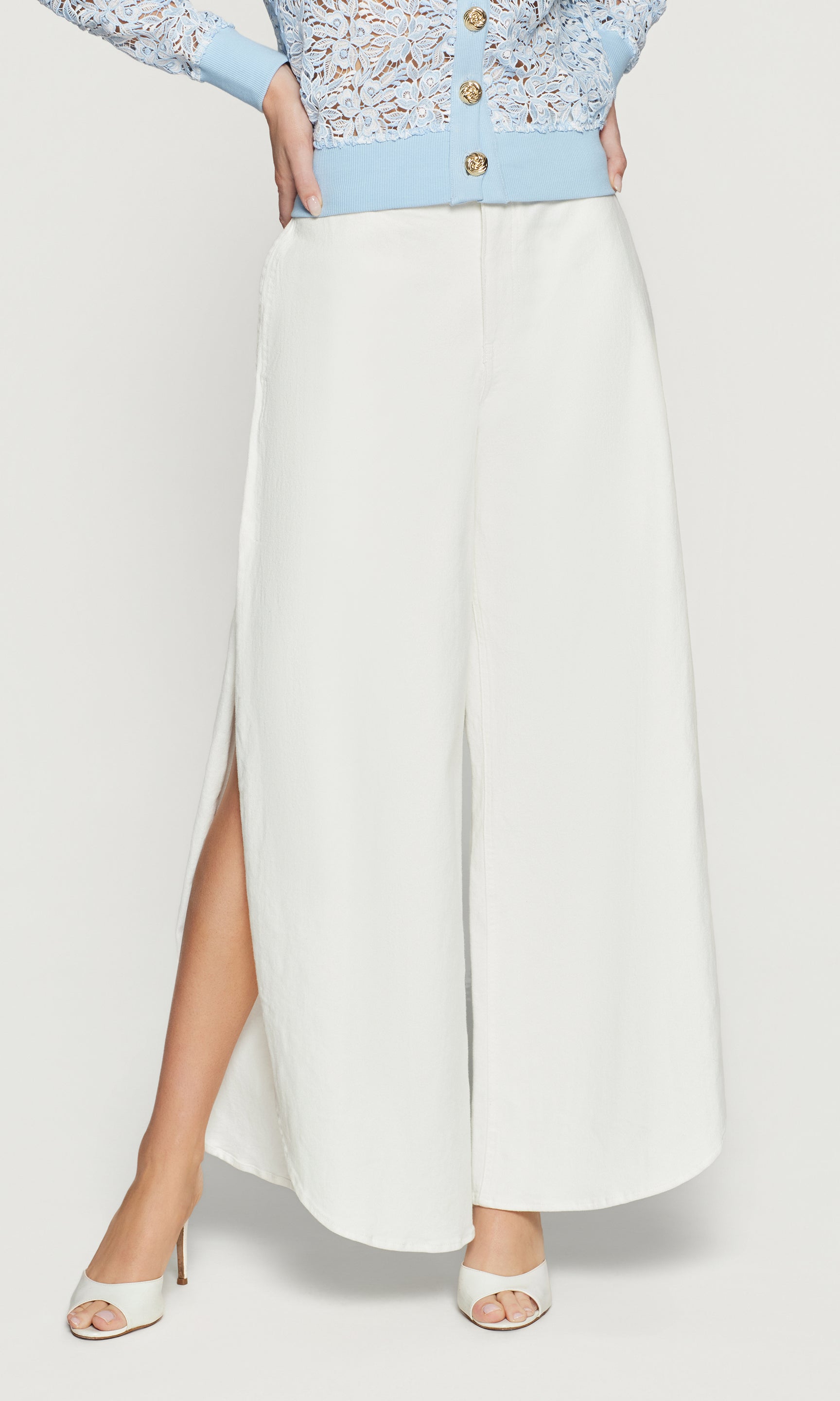 White pants with a high slit worn by a person on a light gray background