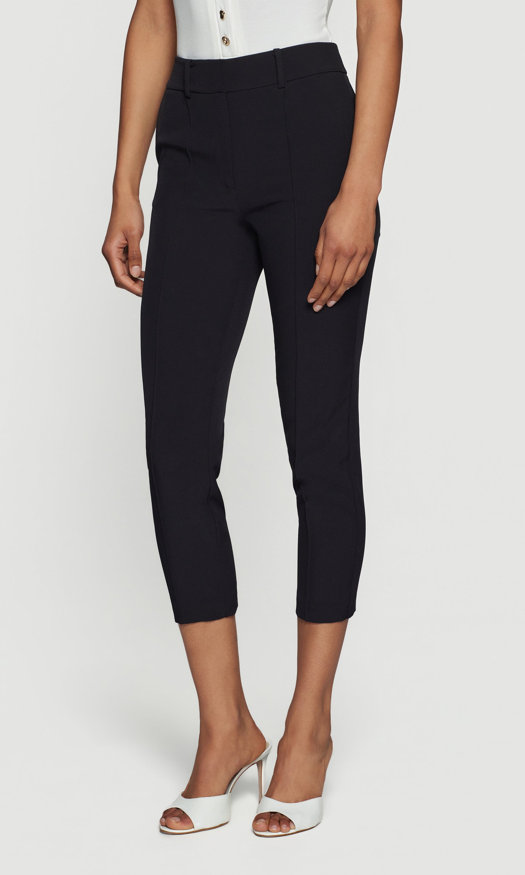 Side view of person wearing black capri pants on a white background