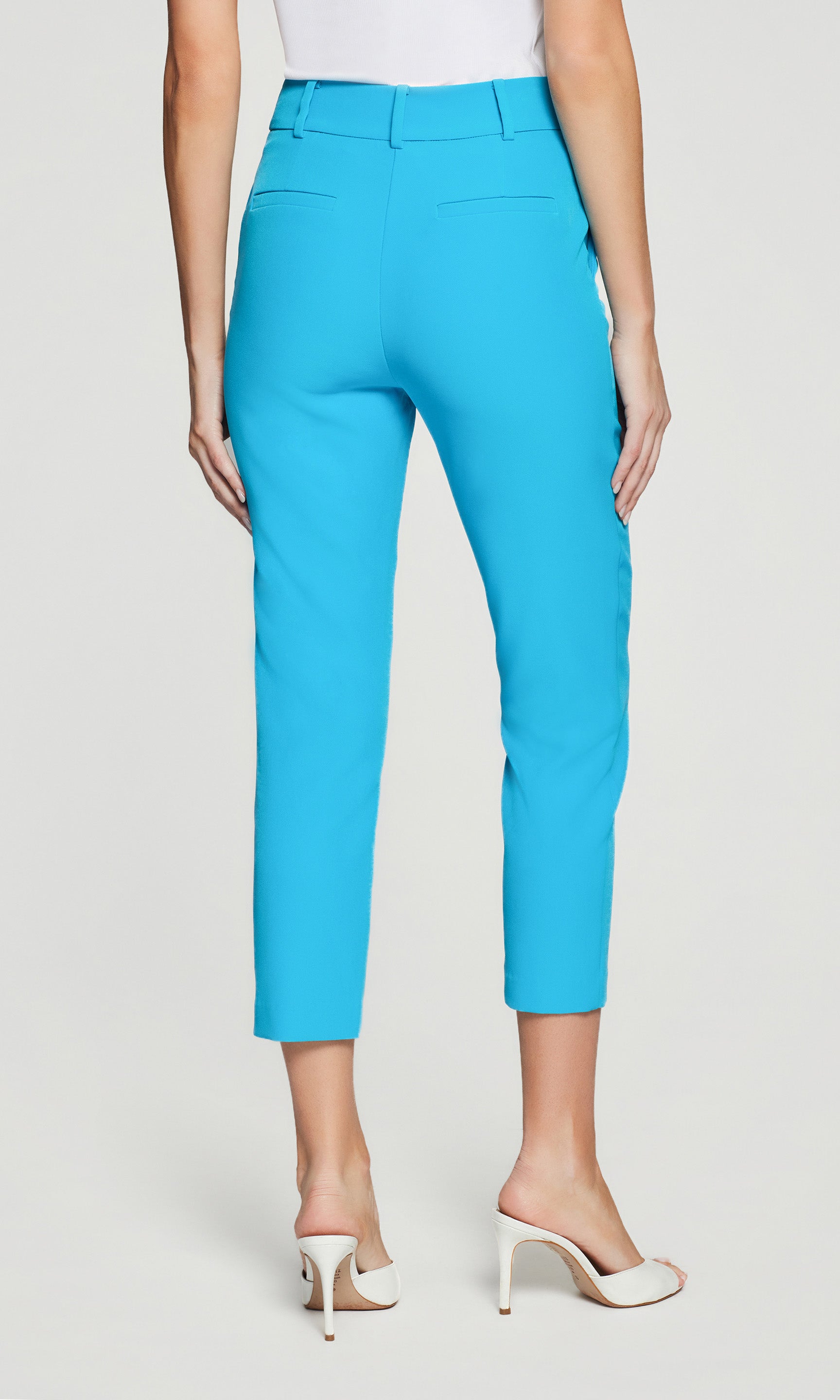 Back view of person wearing bright blue capri pants on a white background