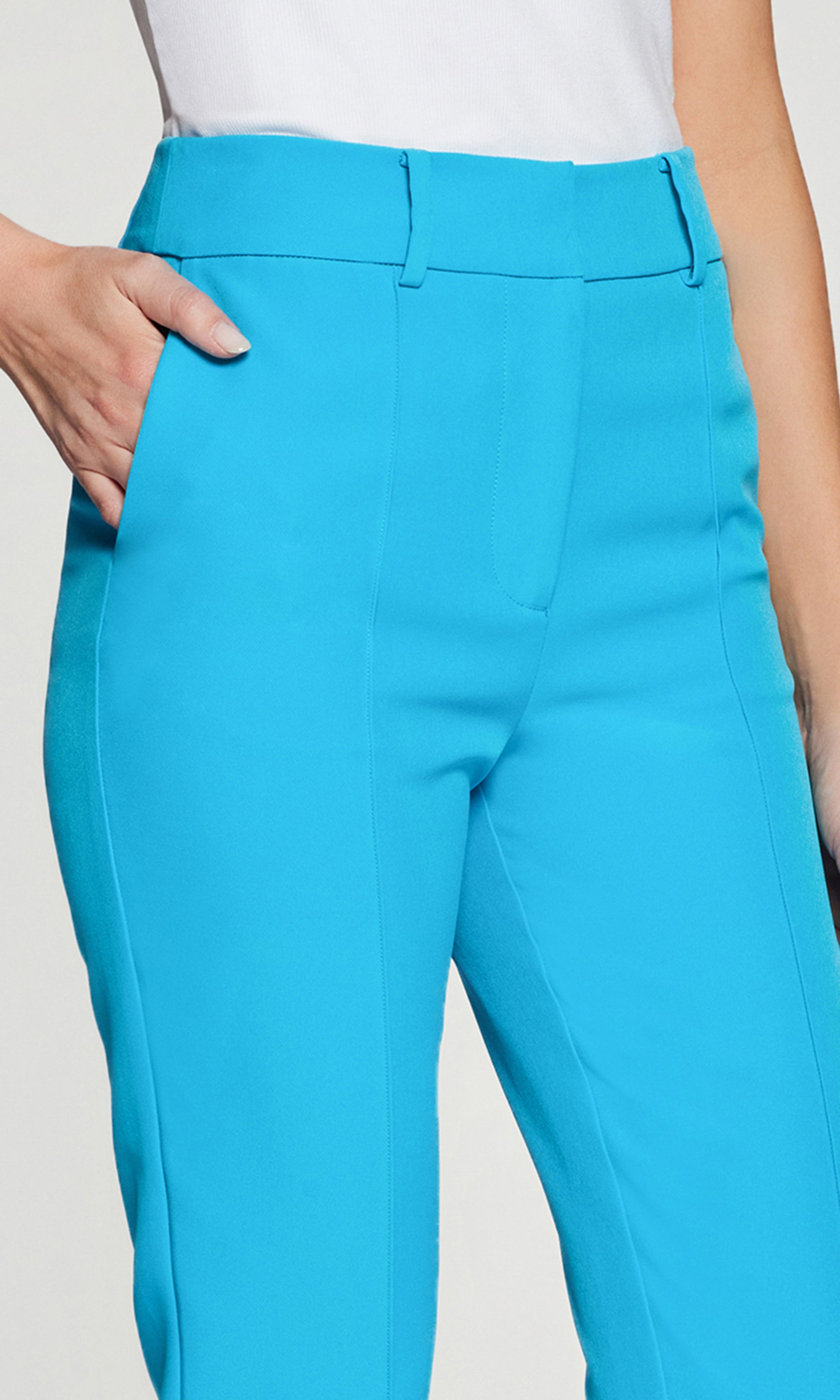 Close-up of turquoise pants worn by a person on a plain background