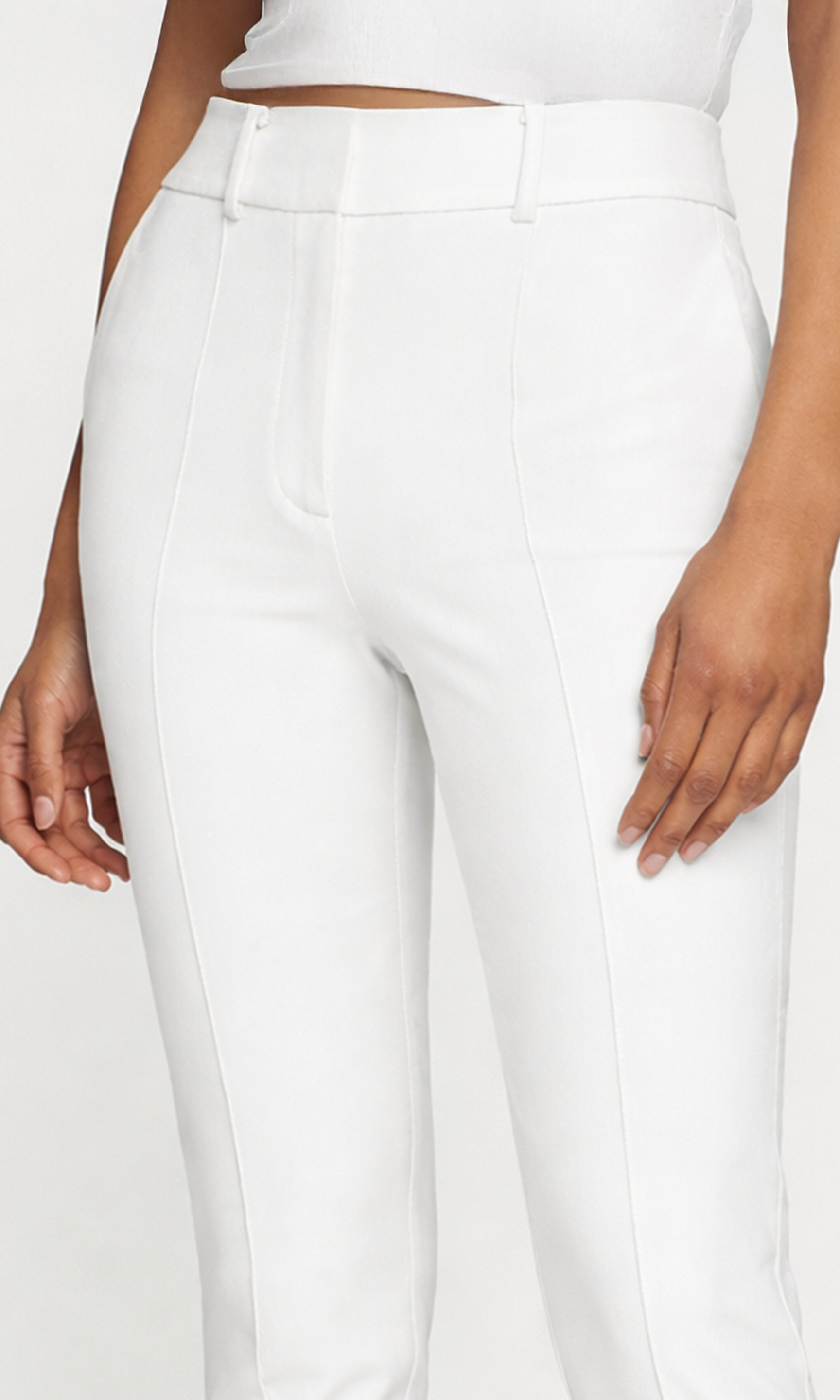 Close-up of white pants worn by a person on a plain background
