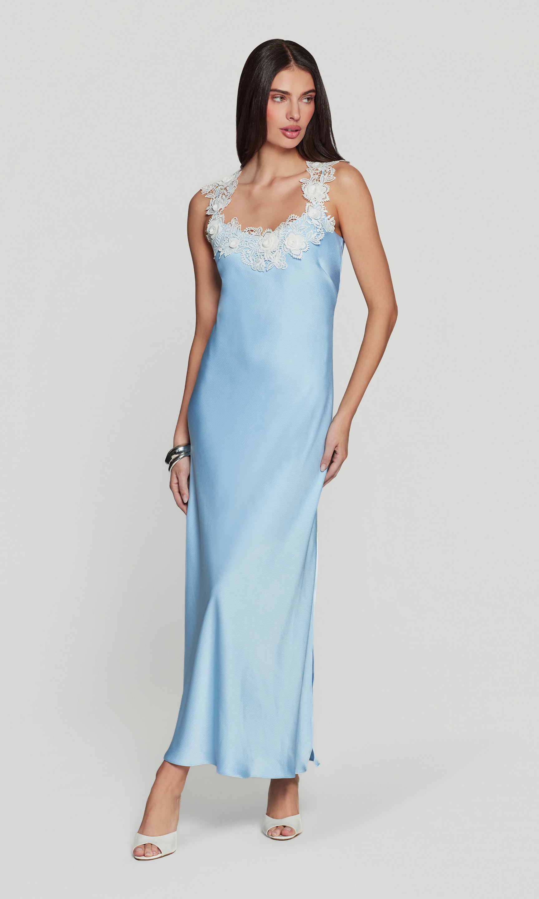 Woman wearing a light blue slip dress with lace details on a white background