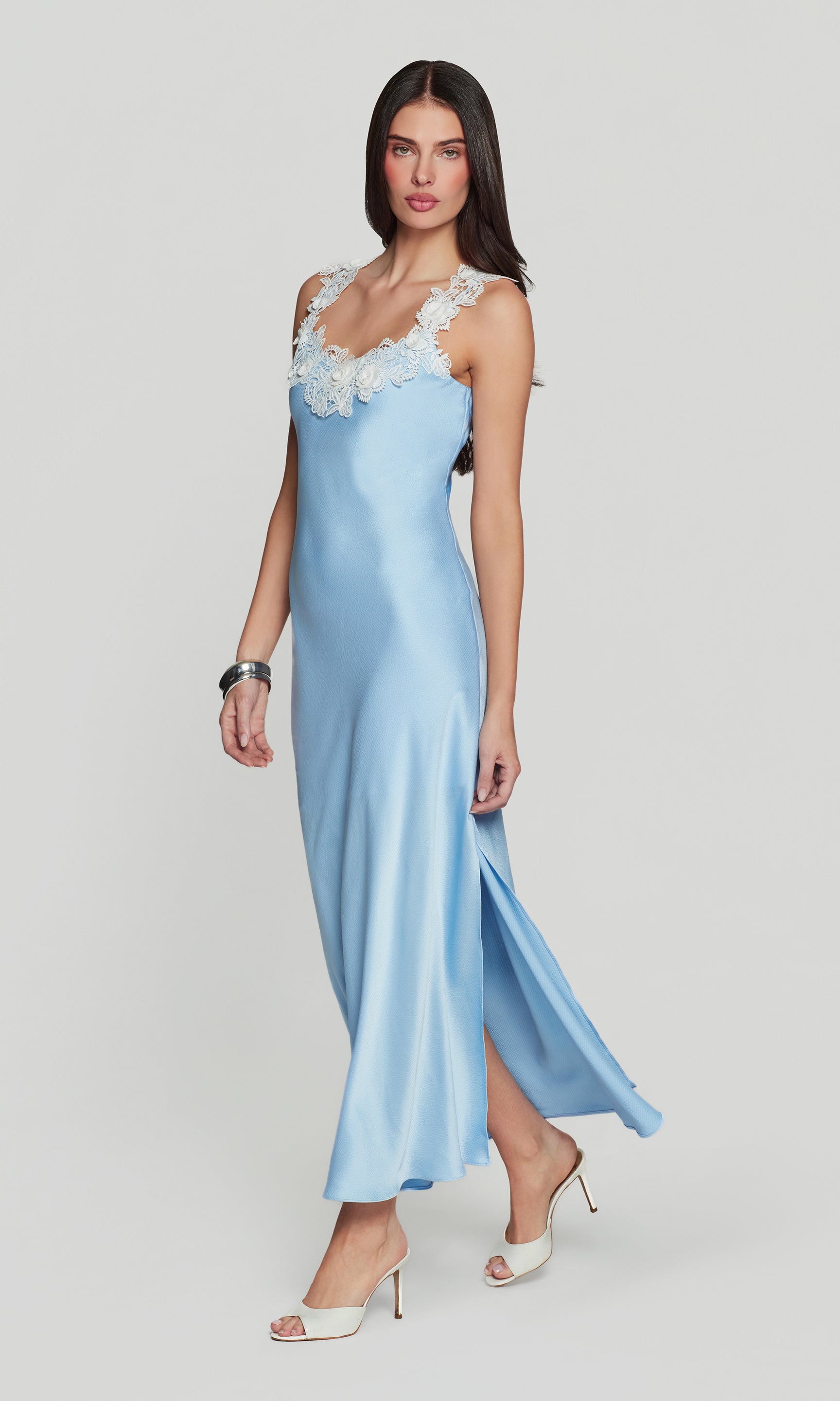 Side view of woman wearing a light blue evening gown with white lace details on a white background