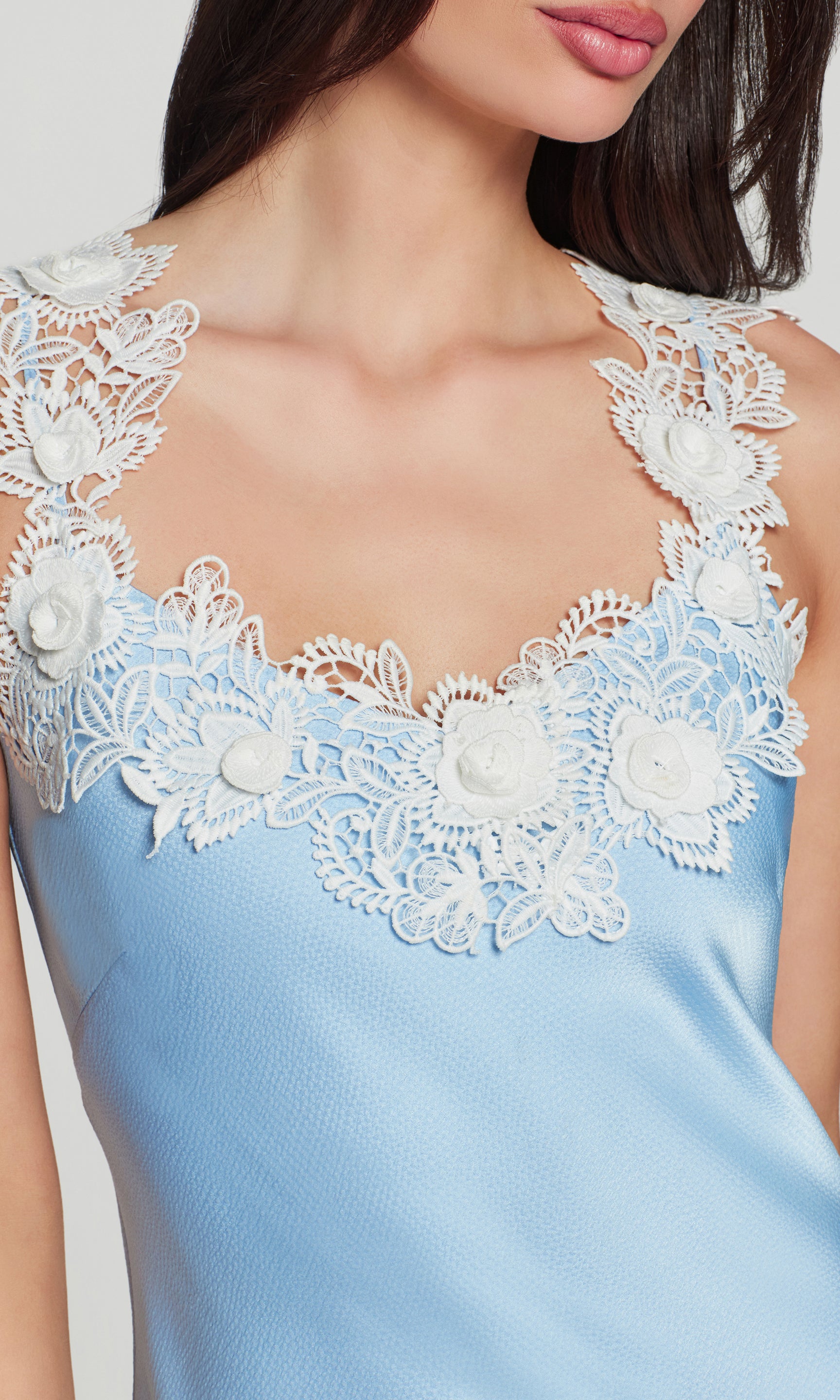 Close-up of light blue dress with white lace and floral details on a plain background