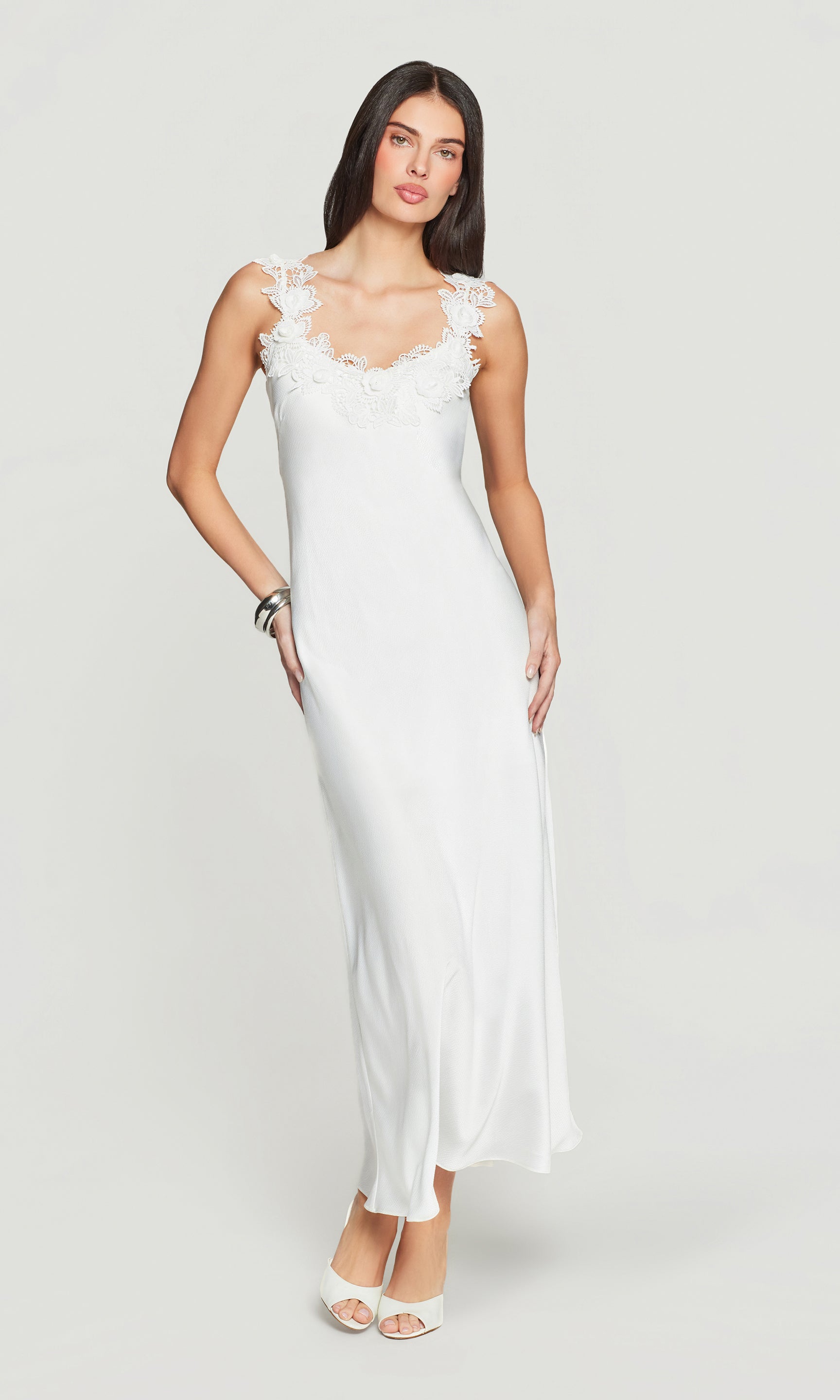 Woman wearing a white sleeveless dress against a plain background
