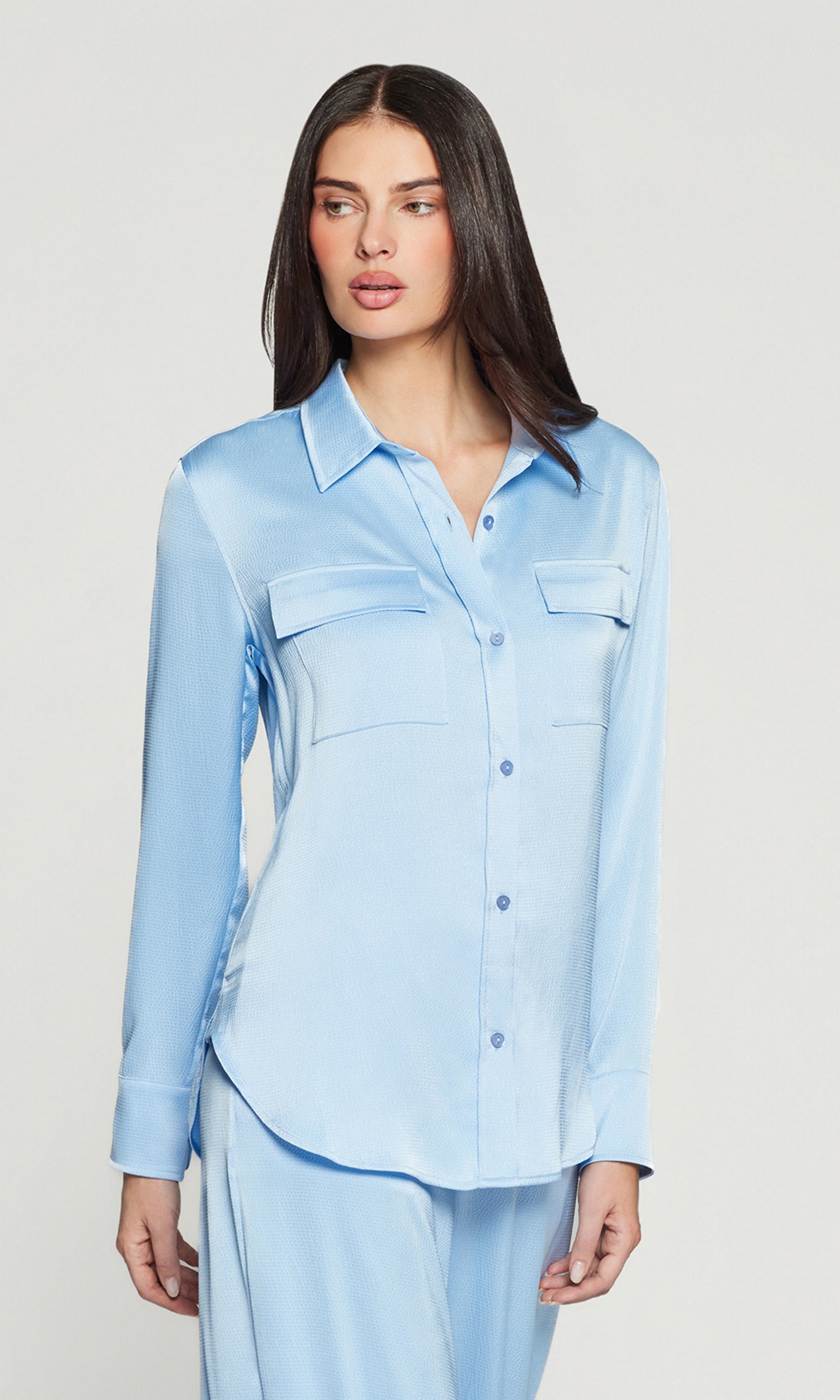 Side view of woman wearing a light blue shirt against a plain background