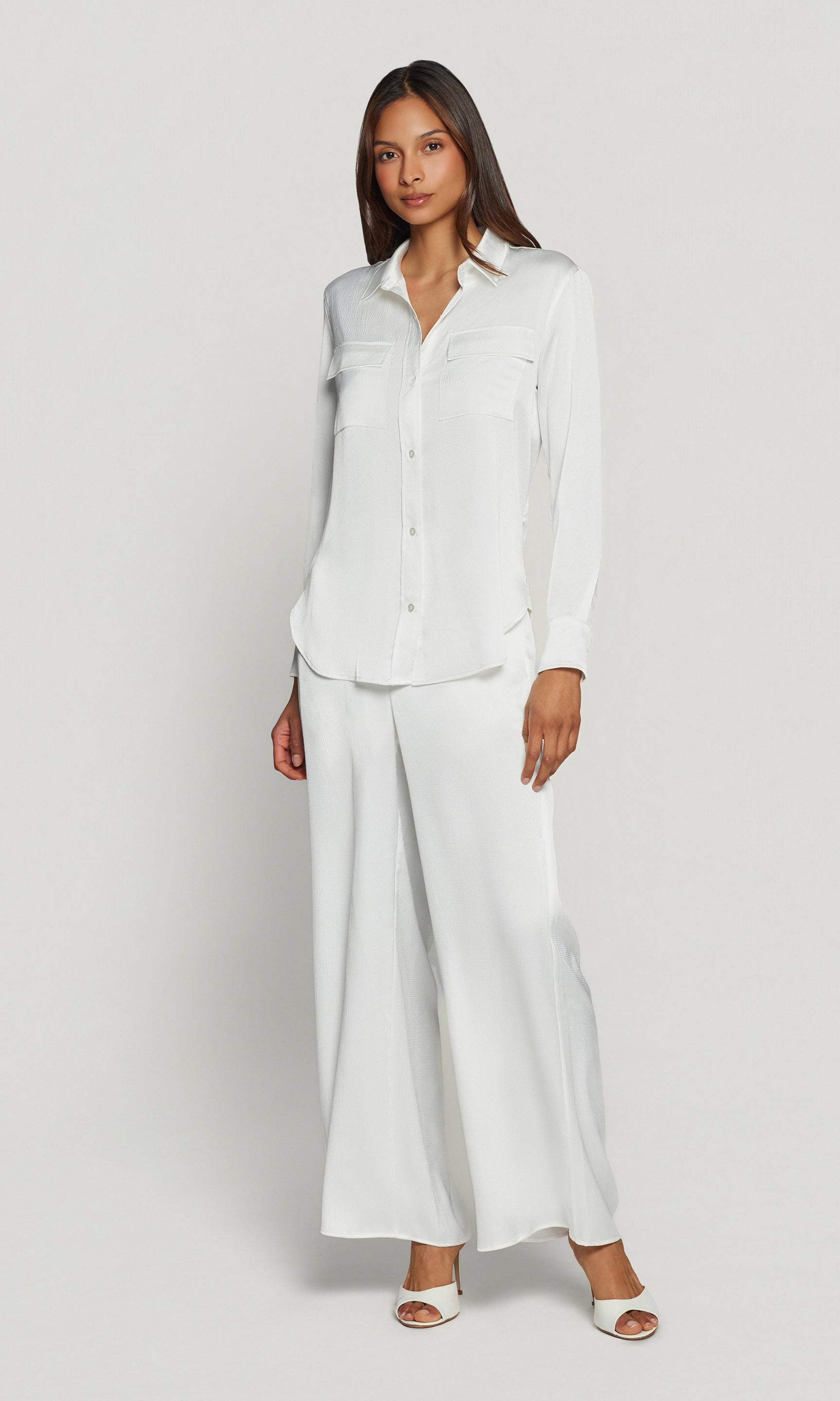 Woman wearing a white satin outfit on a plain background
