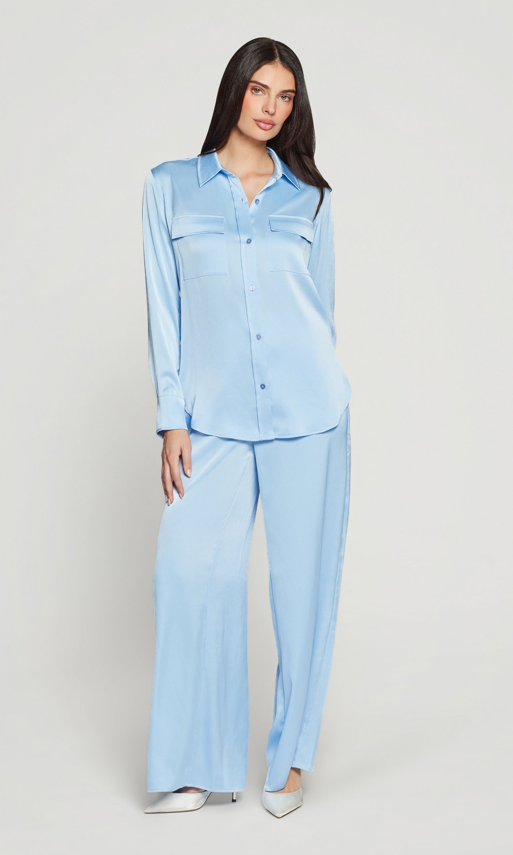Woman wearing a light blue satin outfit on a plain background