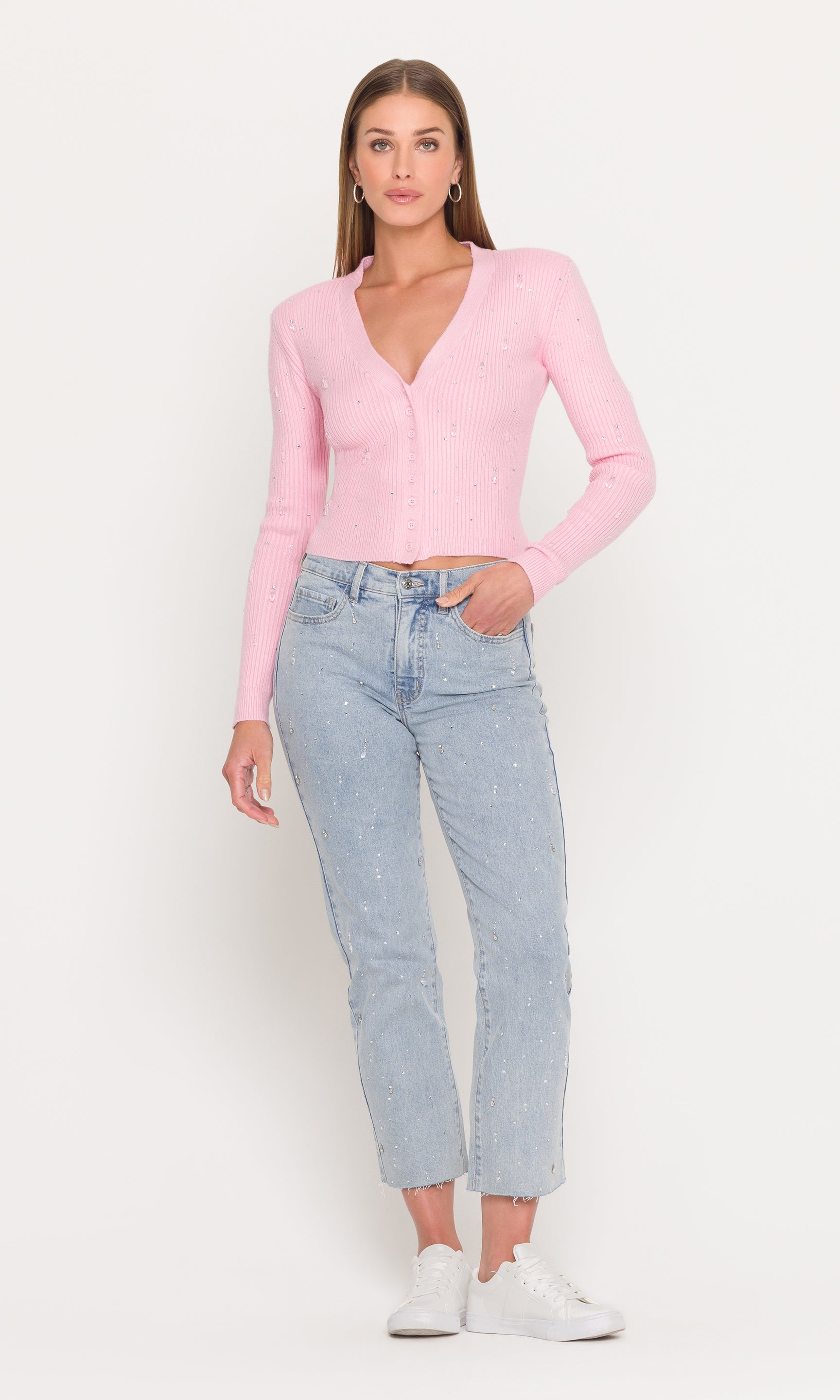 Woman wearing a pink cardigan and light blue jeans on a white background