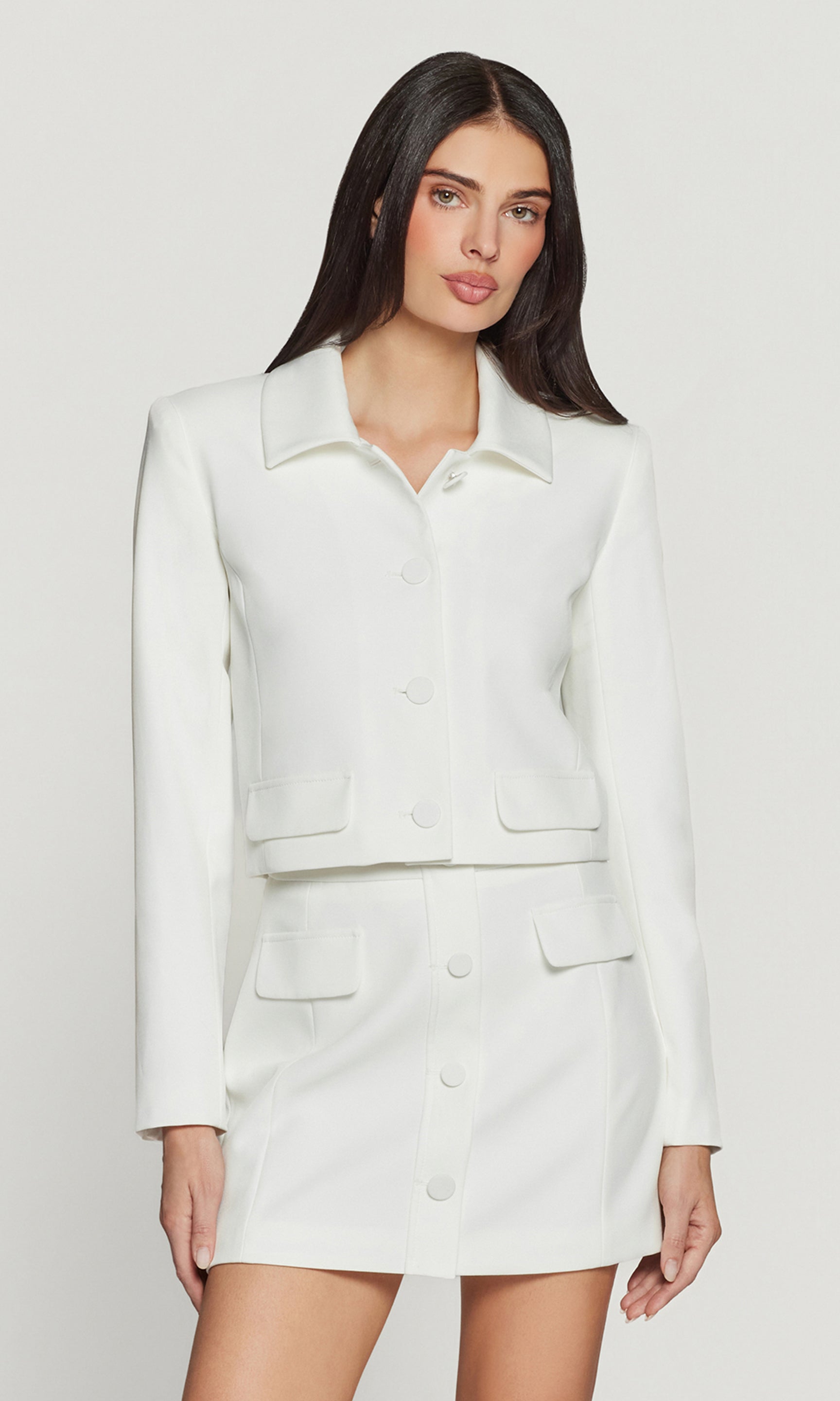 Woman wearing a white suit on a plain background