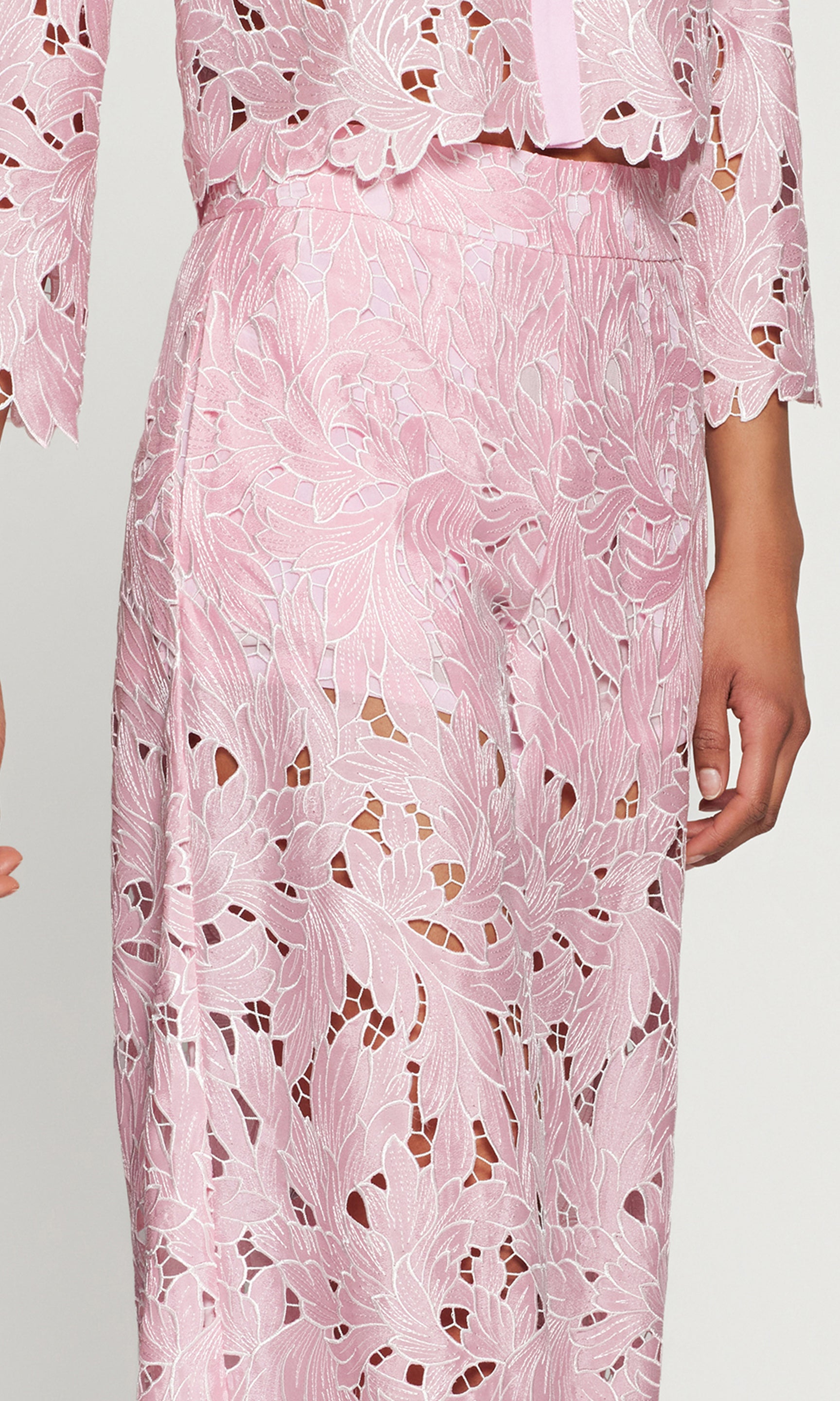 Close-up of pink lace pant with floral patterns on a plain background