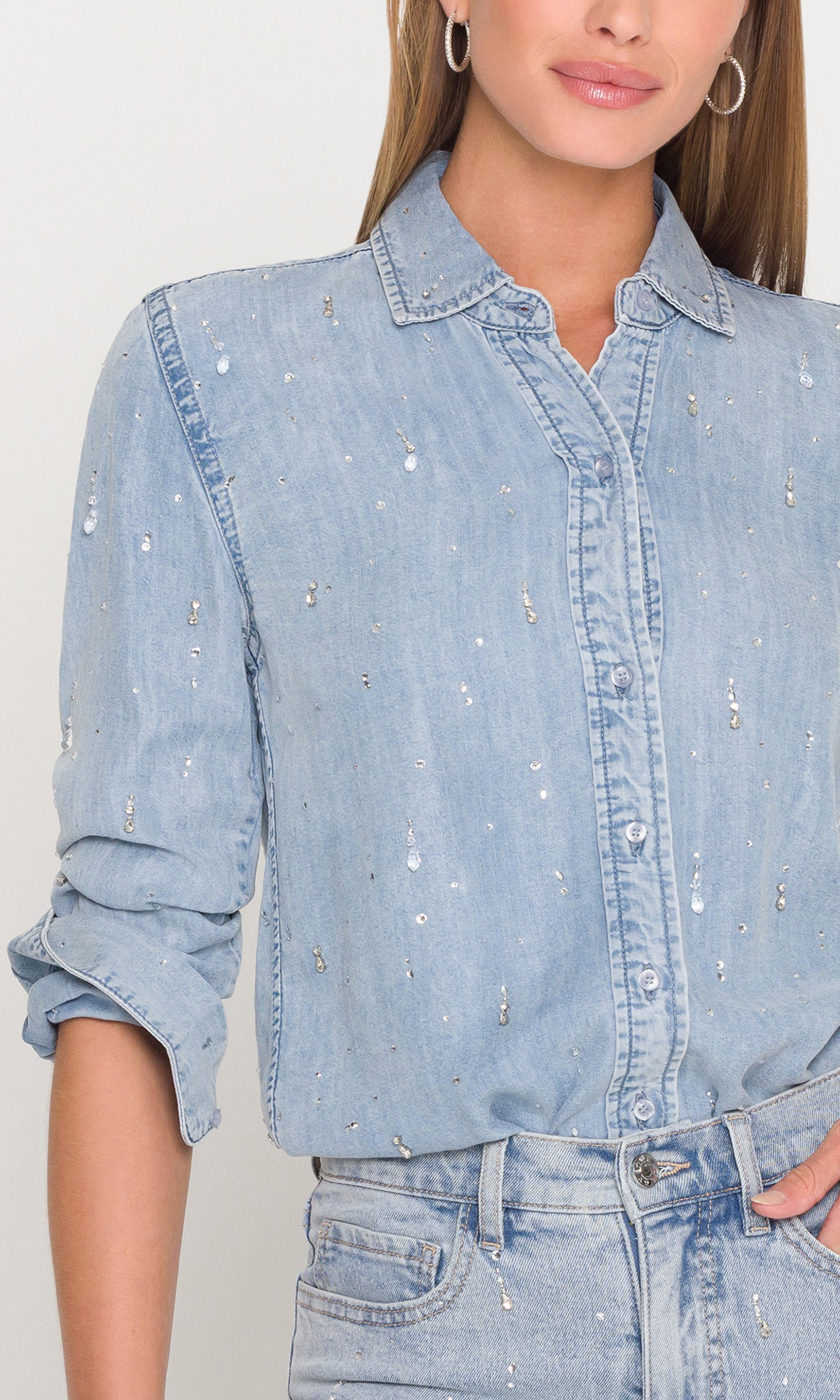 Light blue denim shirt with crystal embellishments worn by a model on a plain background