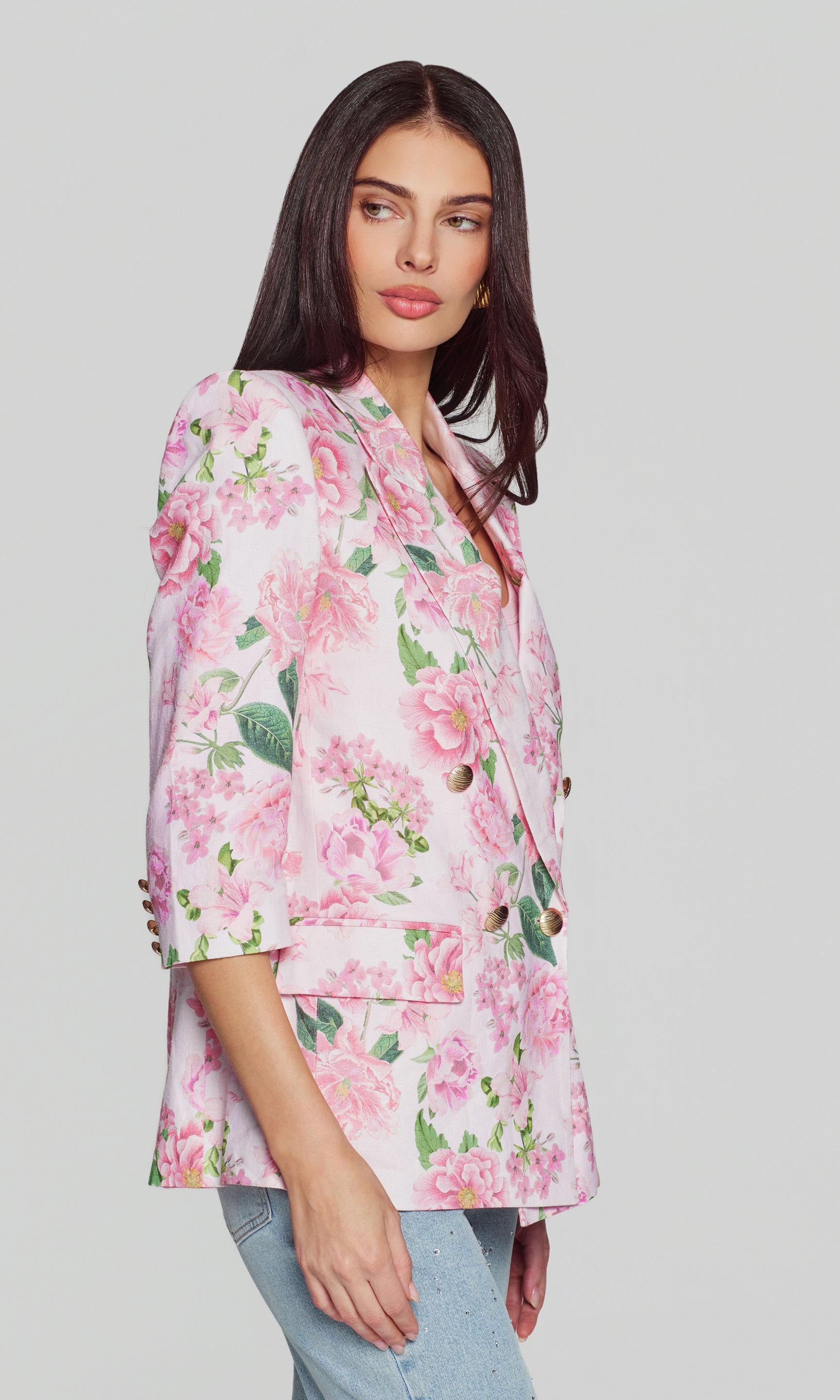 Side view of woman wearing a pink floral blouse against a plain background
