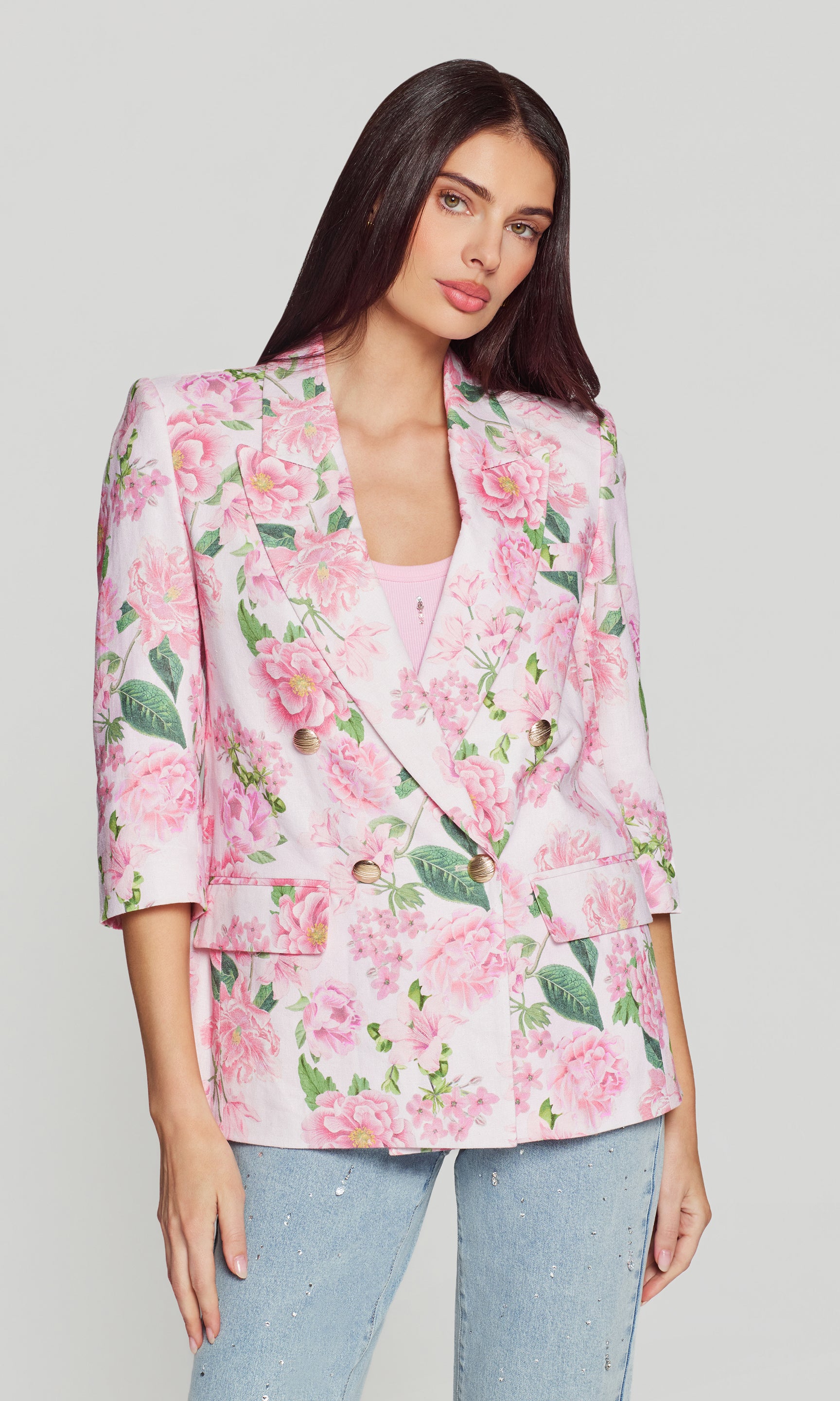 Woman wearing a pink floral blazer on a plain background