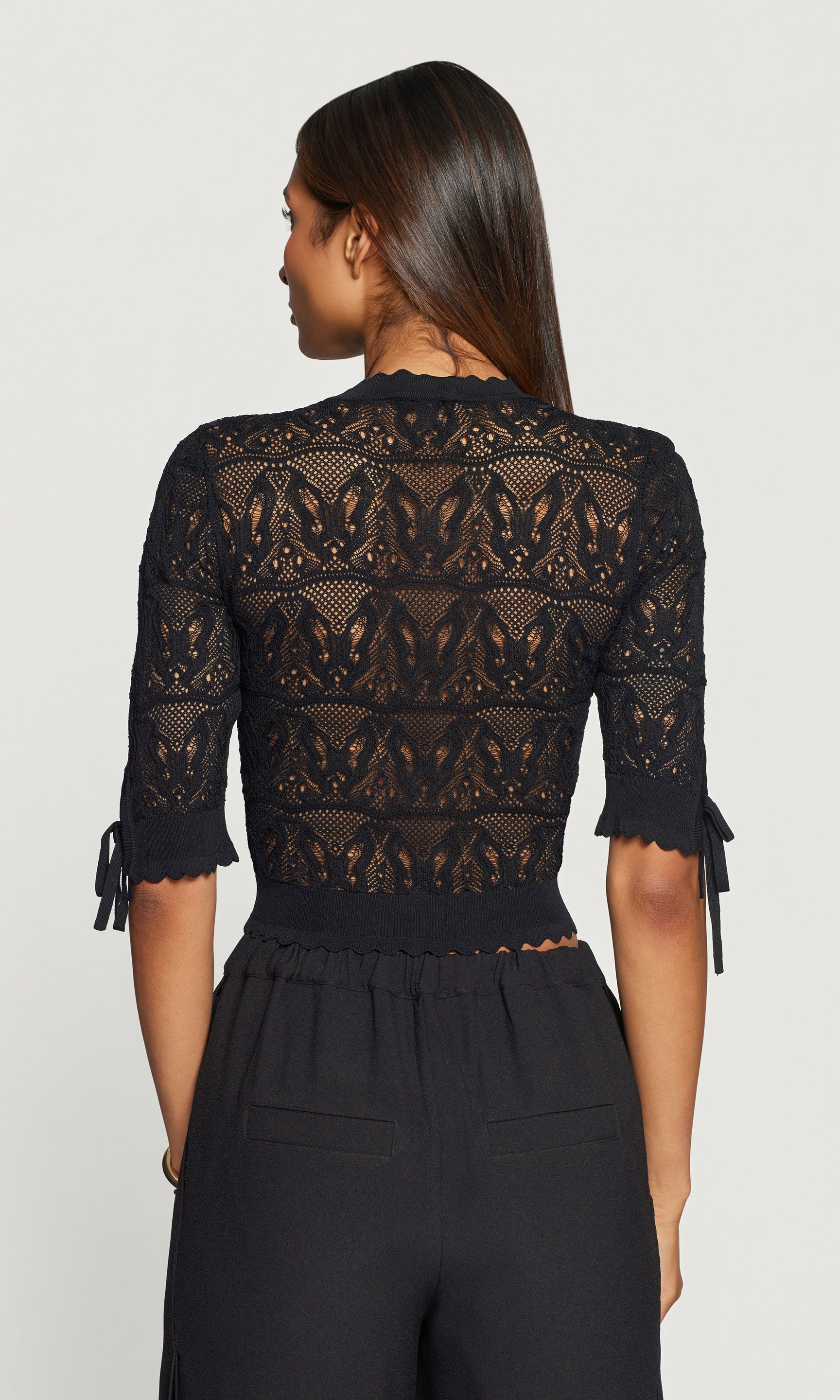Back view of black pointelle cardigan with black pants