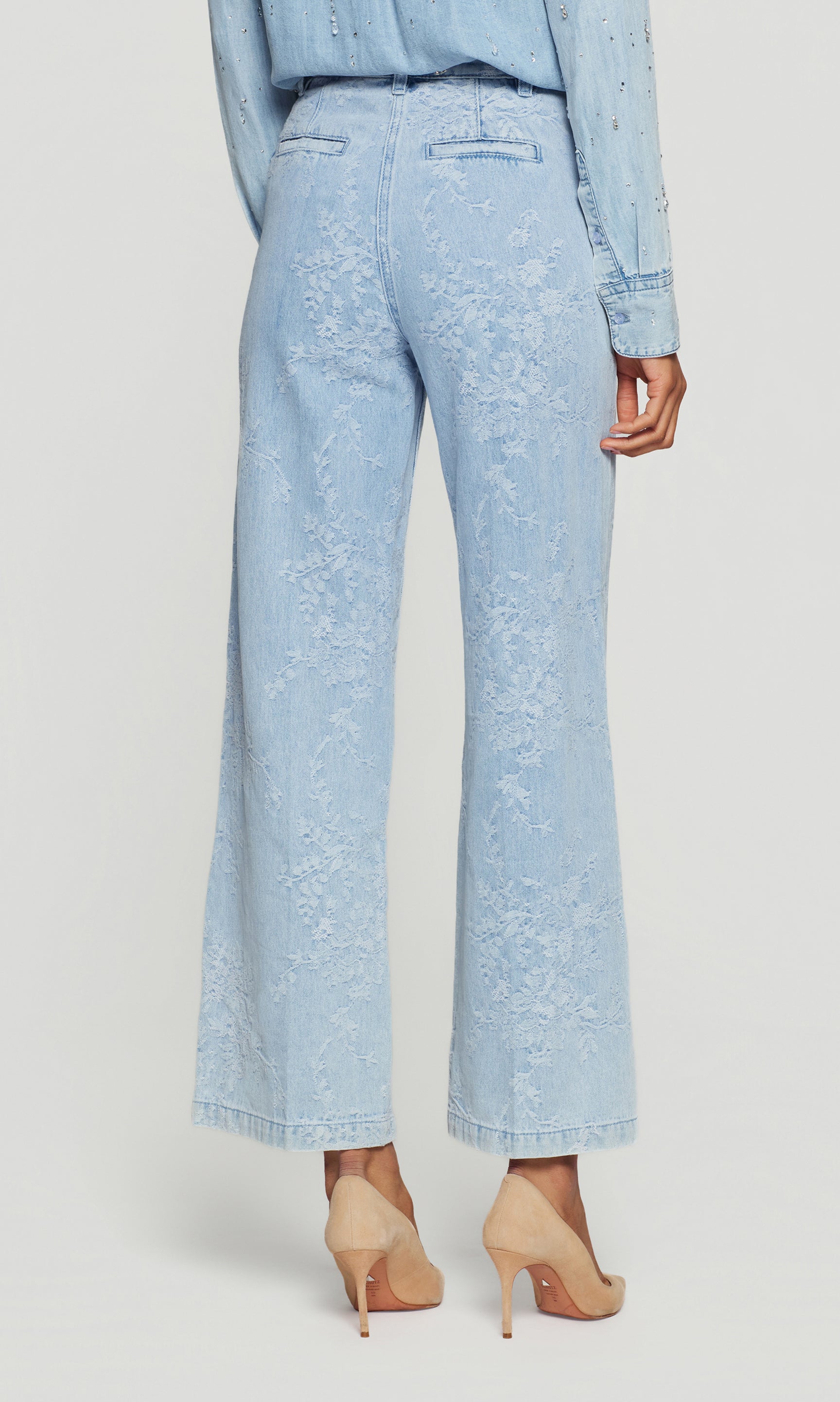 Back view of light blue denim pants worn by a person on a white background