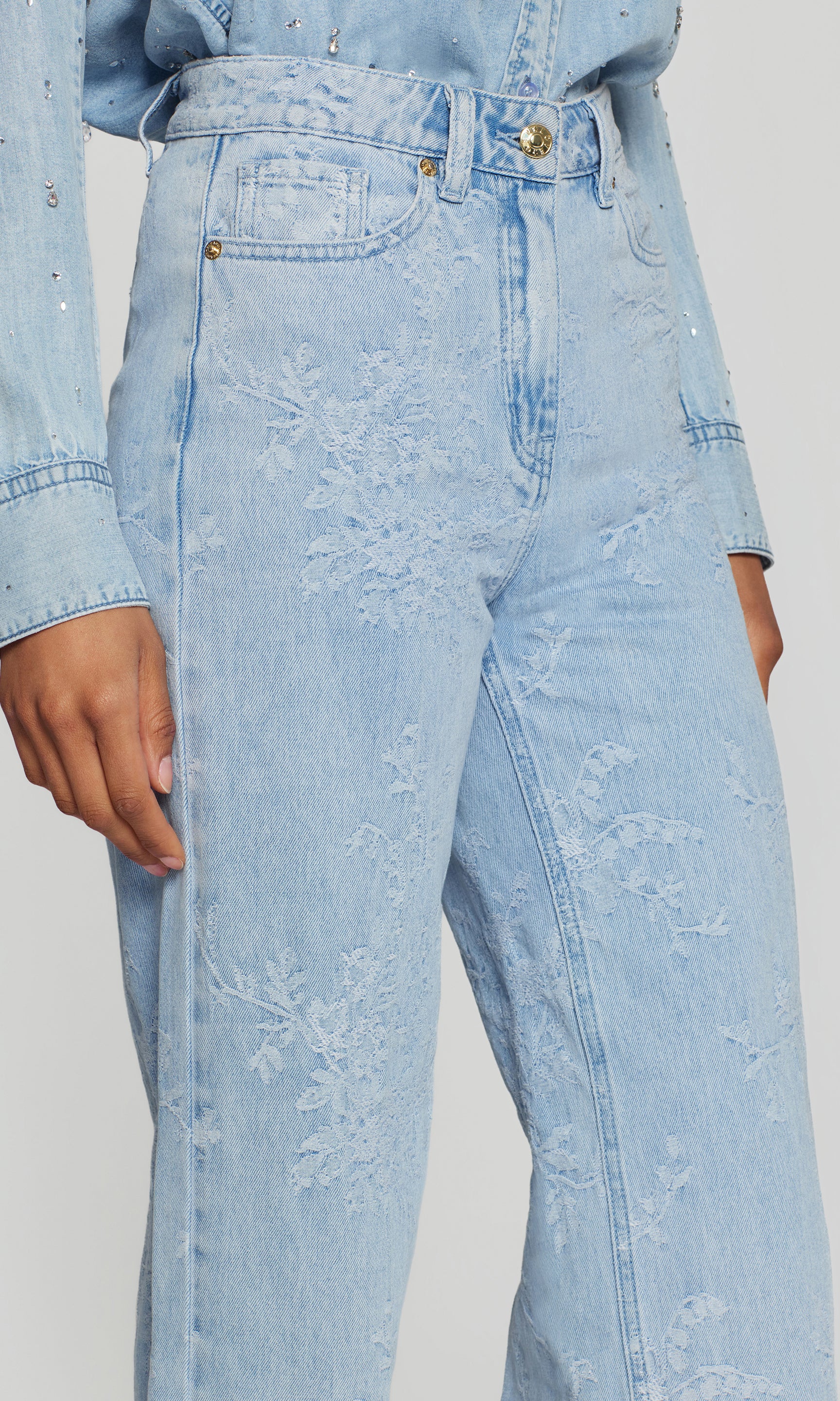 Close-up of light blue acid-wash jeans worn by a person on a plain background