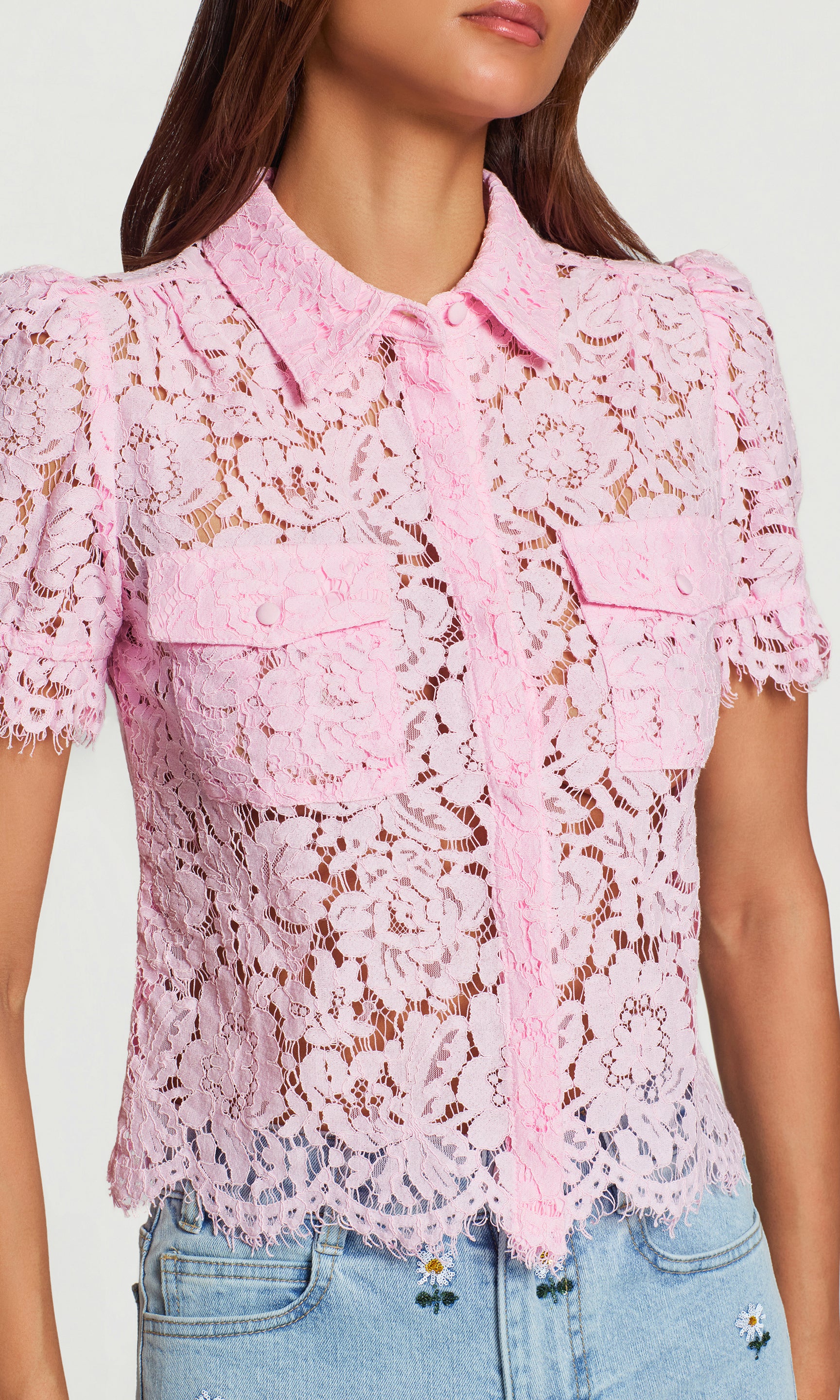 Close-up of pink lace blouse worn by a person on a white background