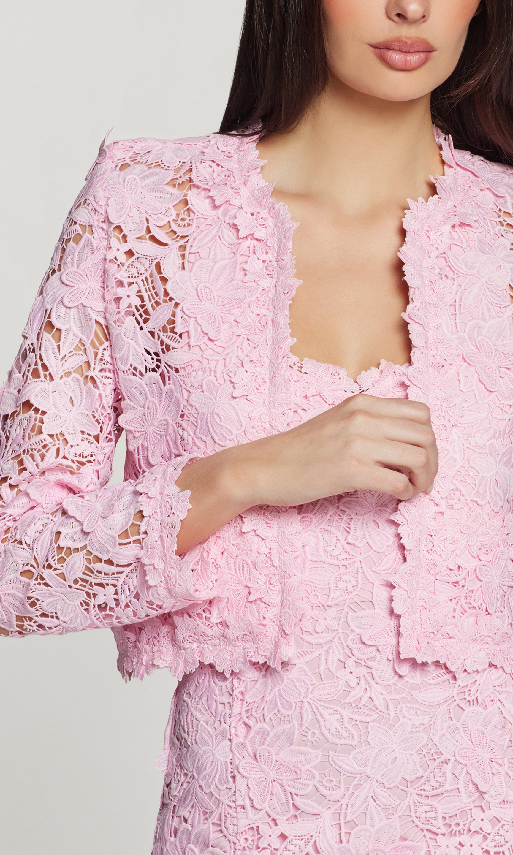 Close-up of pink lace jacket worn by a model on a light gray background