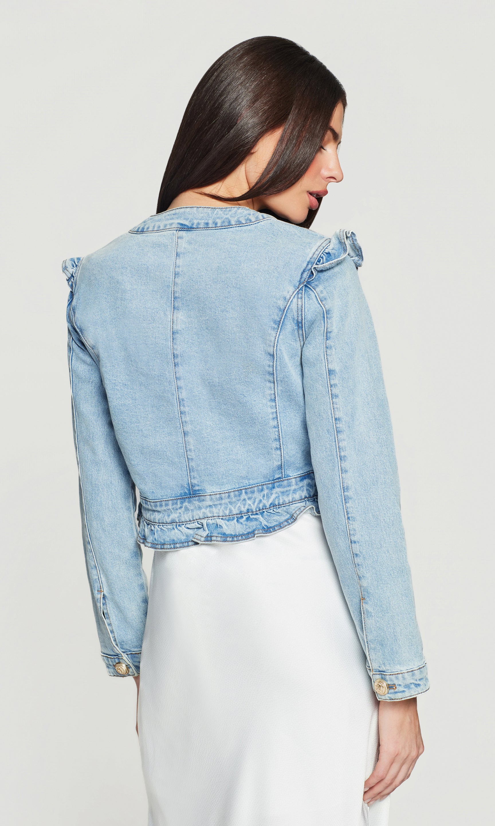 Back view of light blue denim jacket worn by a person on a plain background