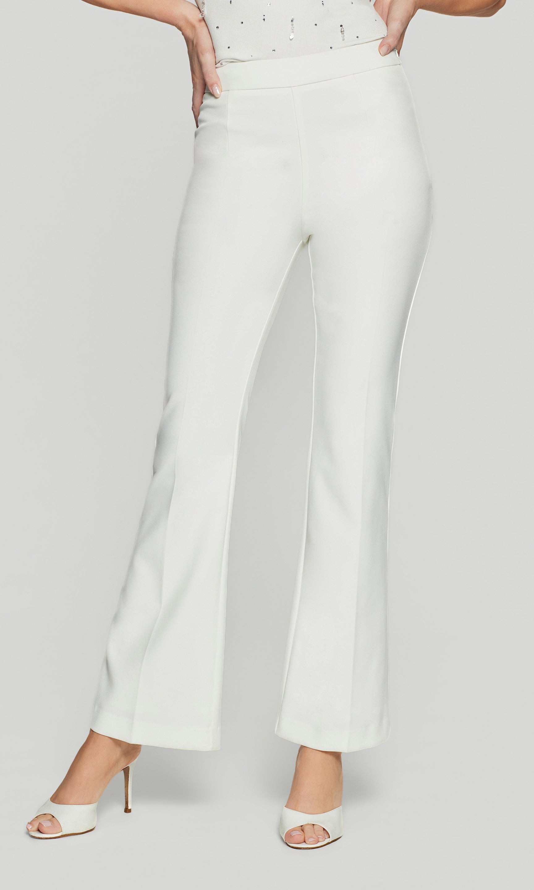 White high-waisted pants worn by a person on a light gray background