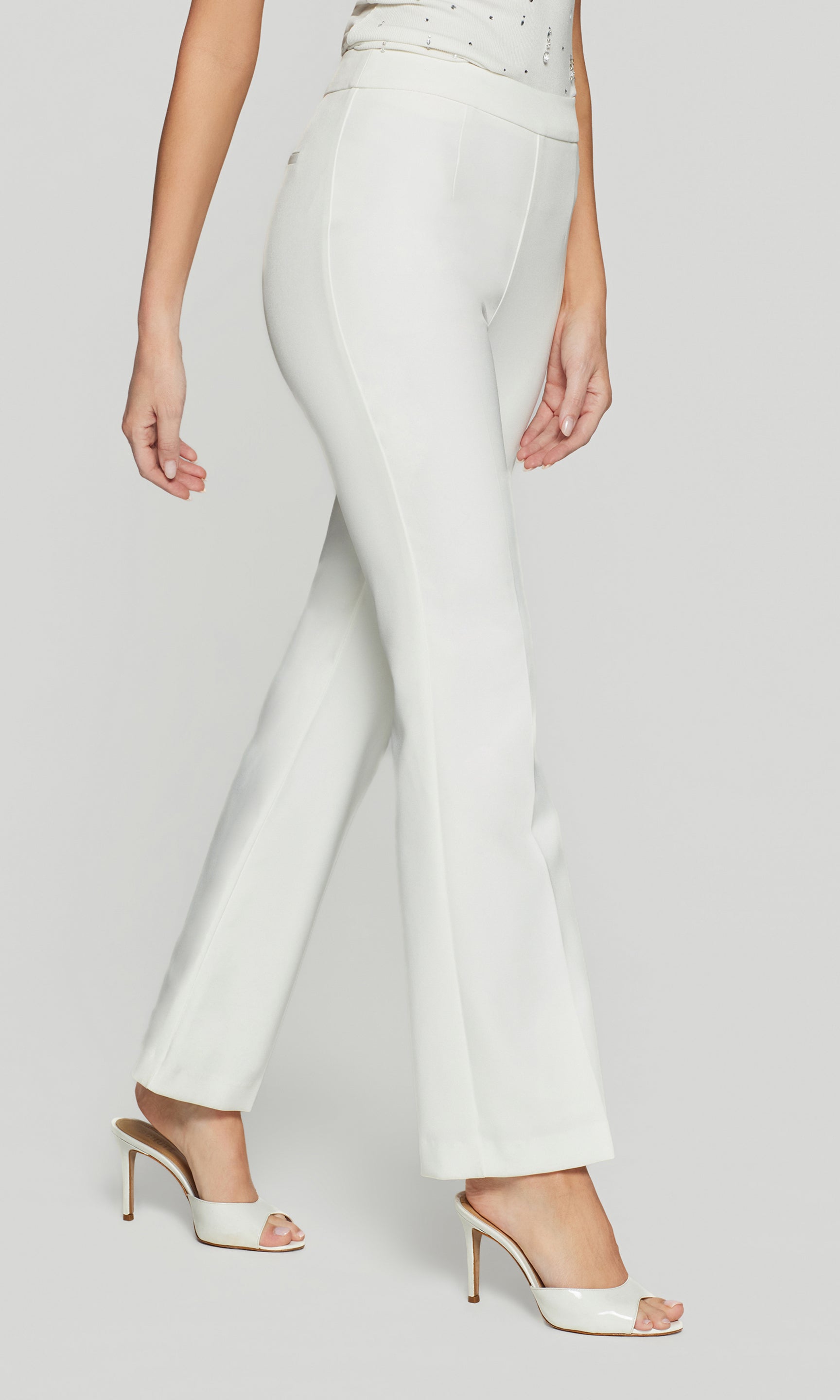 Side view of white pants worn by a person on a light gray background